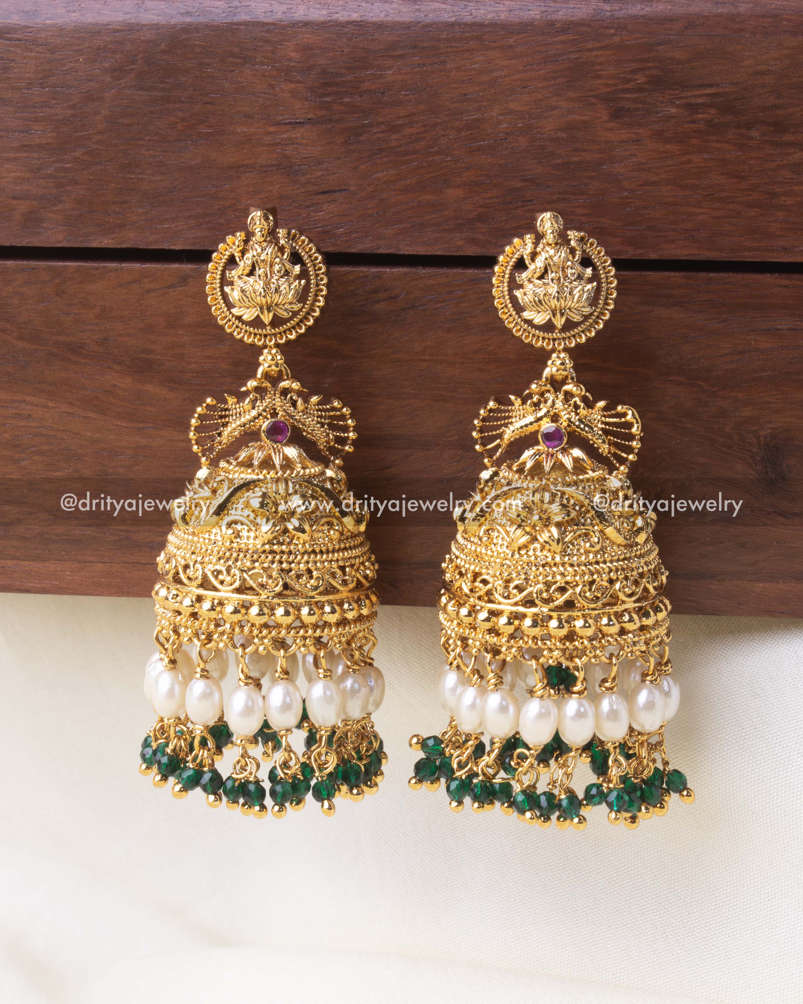 Gold-plated temple Jhumka earrings featuring pearl drops and green crystal beads.