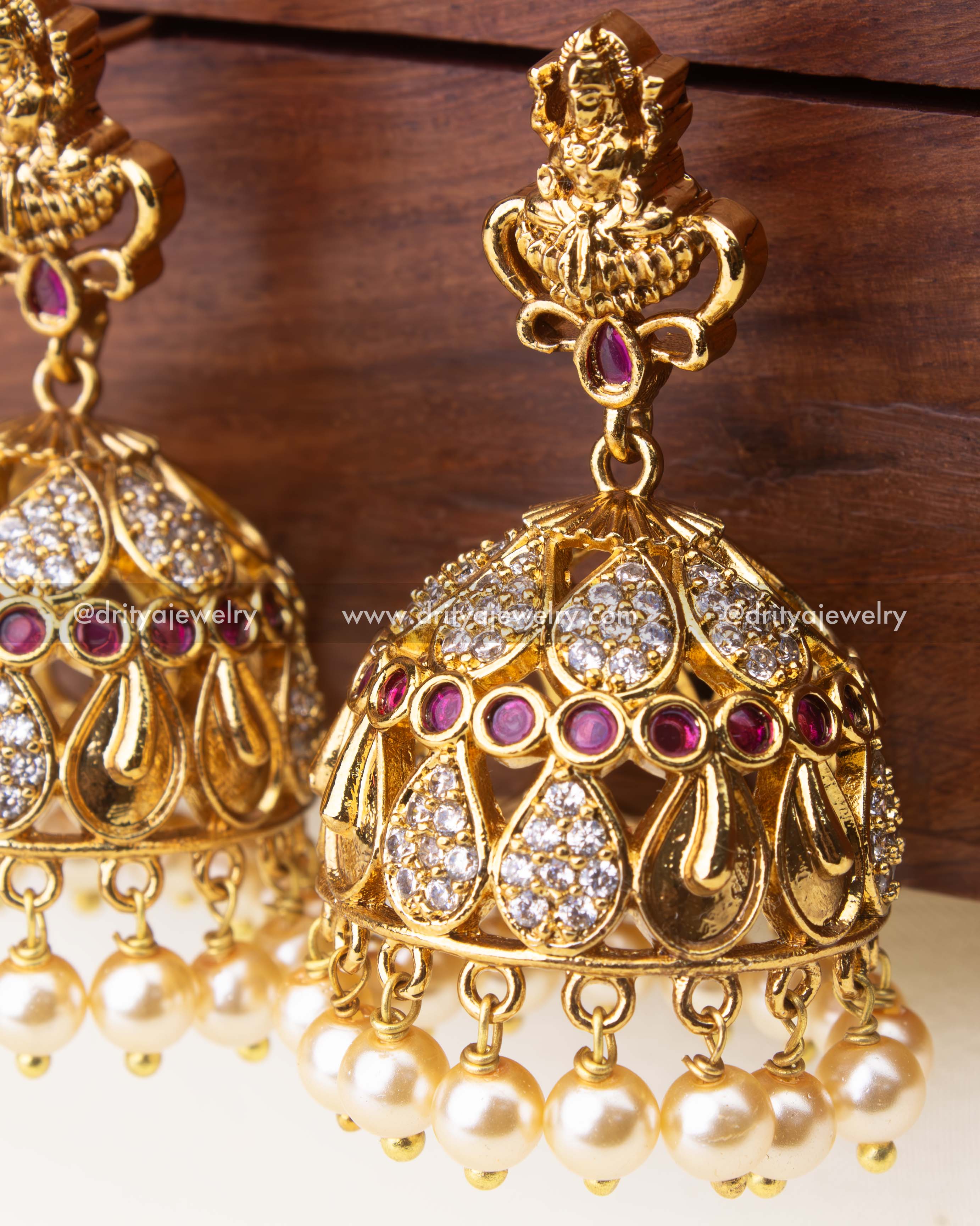 Intricate temple-style jhumka earrings with ruby accents, CZ detailing, and pearl hangings.