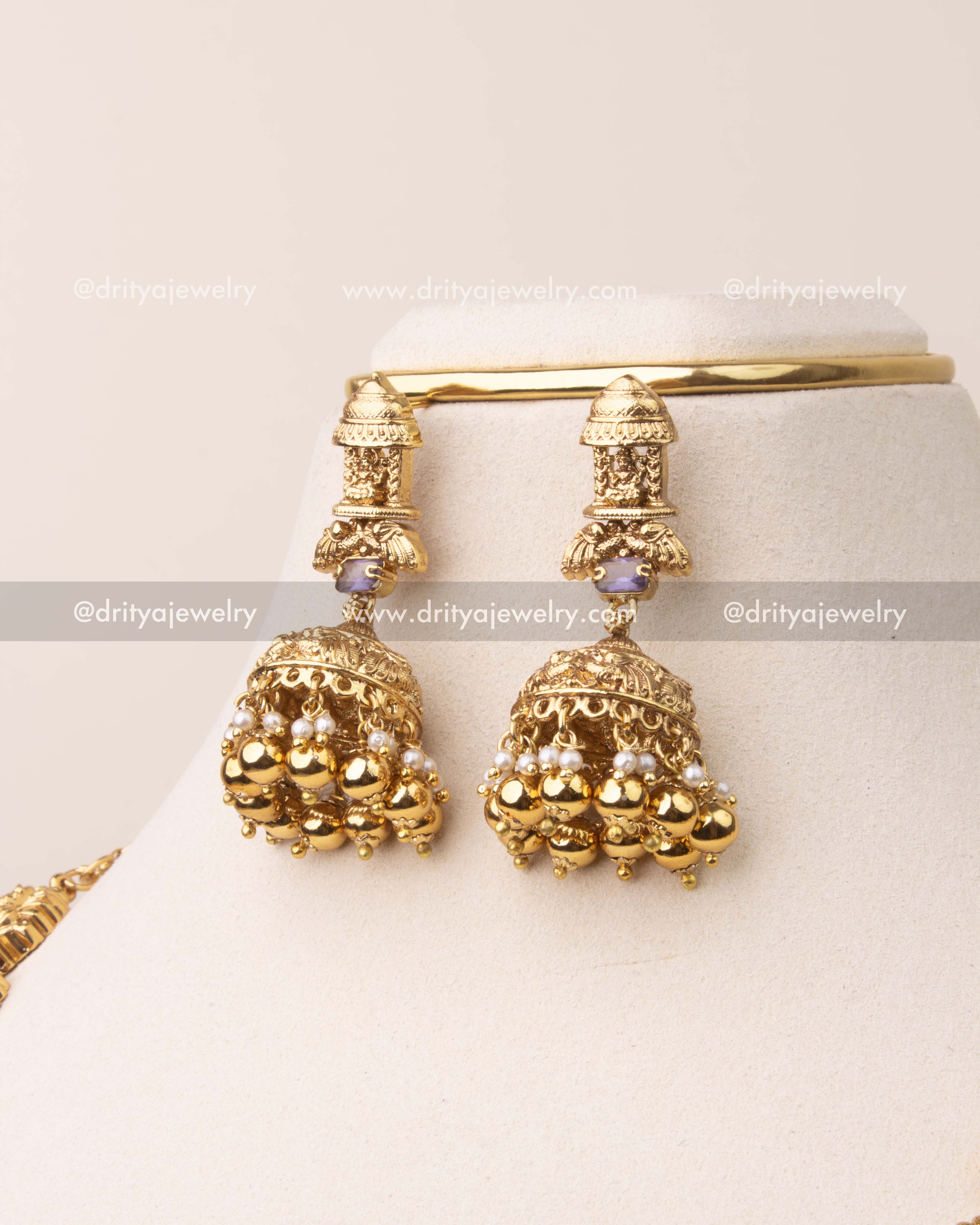 Traditional temple-style jhumka earrings with violet stones, gold beads, and pearl accents.