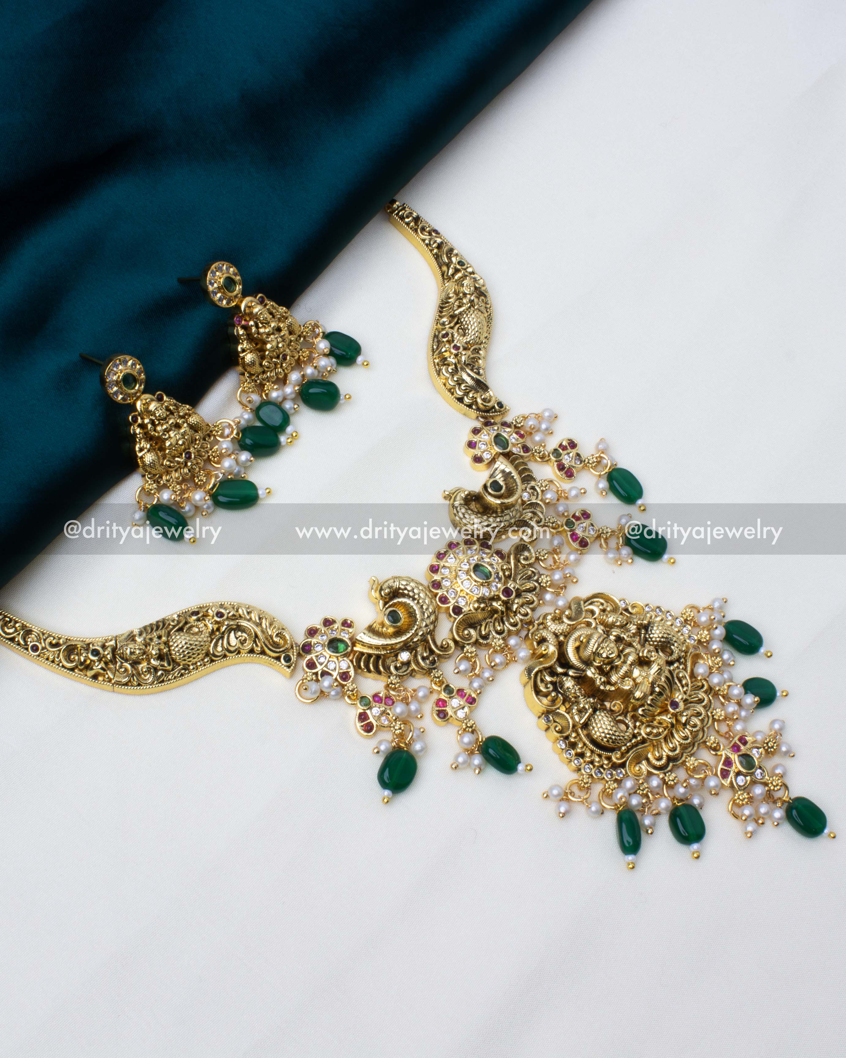 Temple Kanti necklace set in antique gold polish with deity motifs, green beads, and pearls.