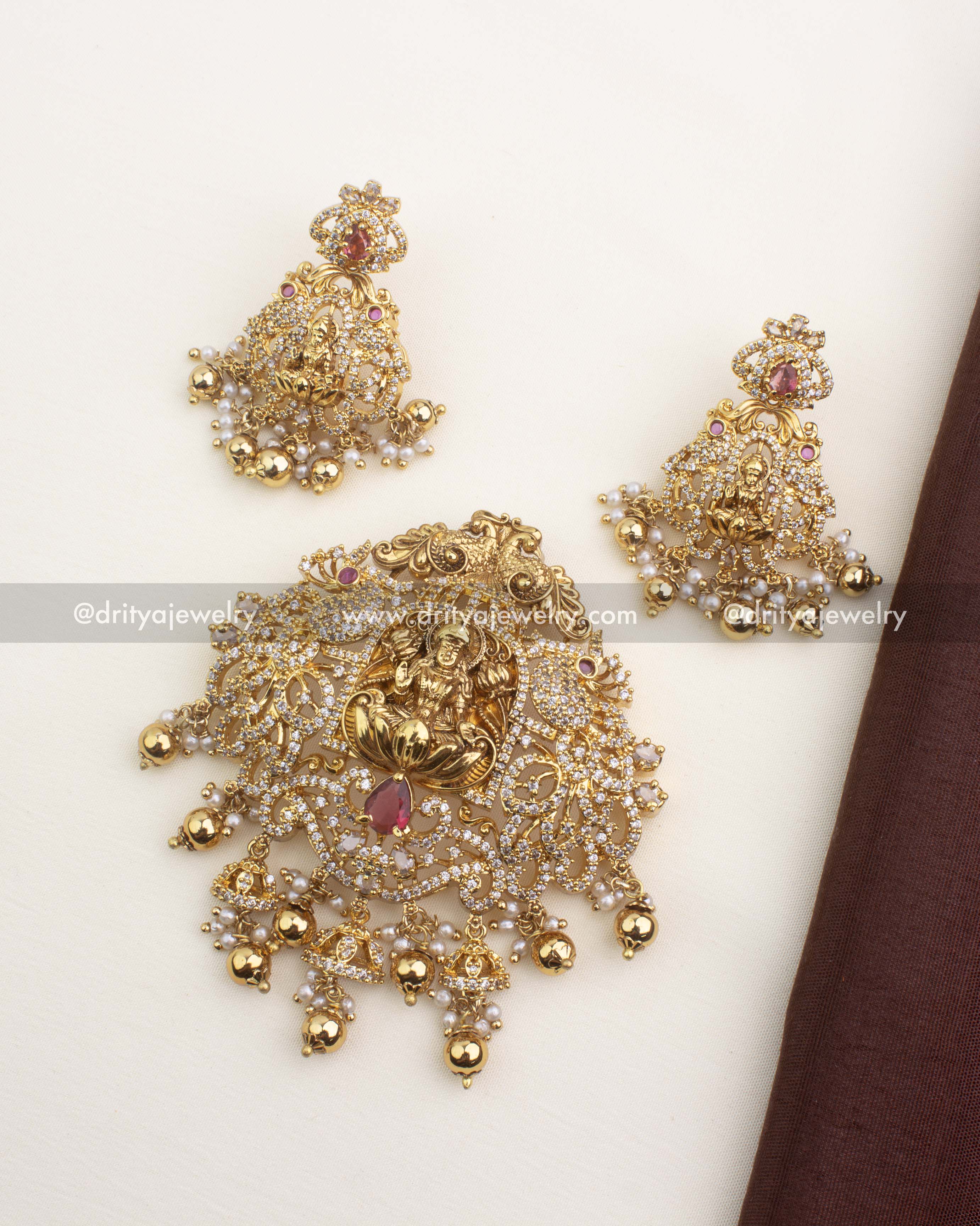 Traditional gold temple pendant set featuring Lakshmi, CZ stones, and a red centerpiece stone.