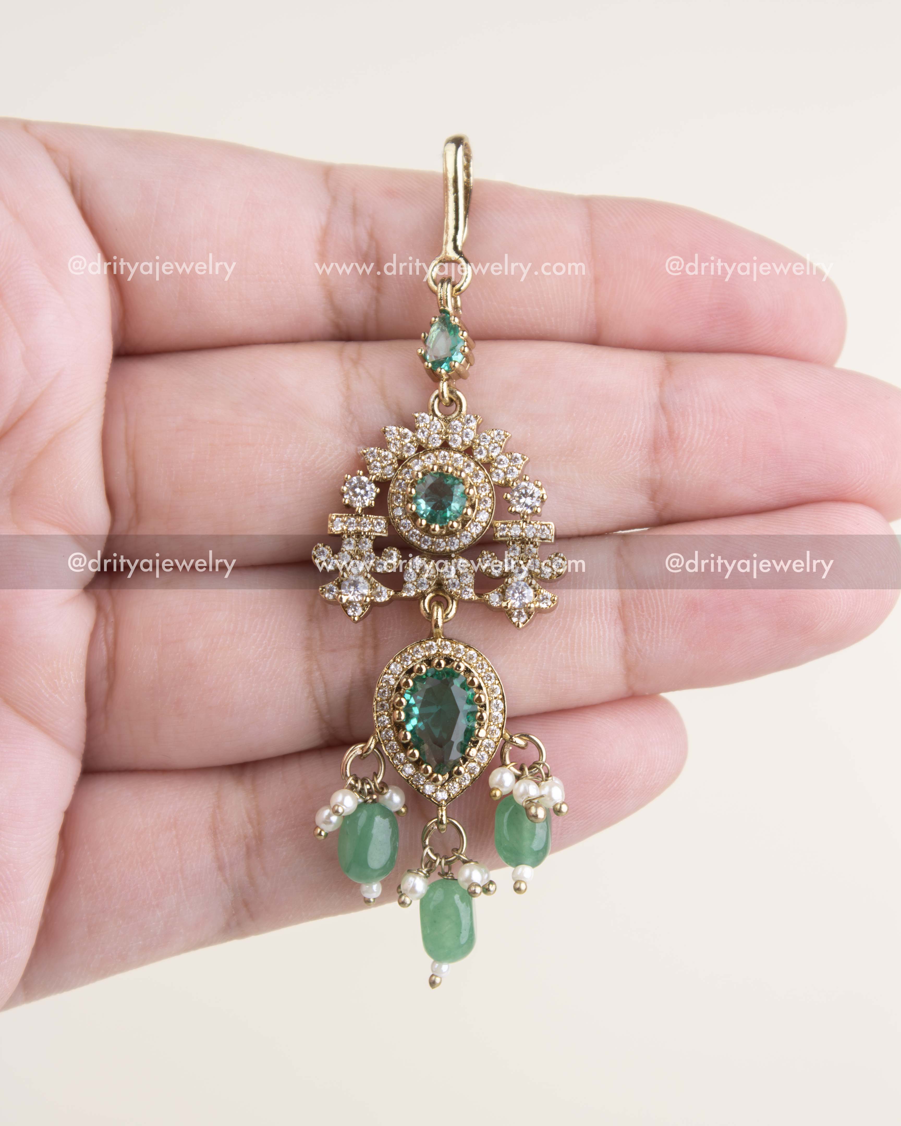 Russian emerald maang tikka with AD stones, floral motif, and Victorian gold polish.