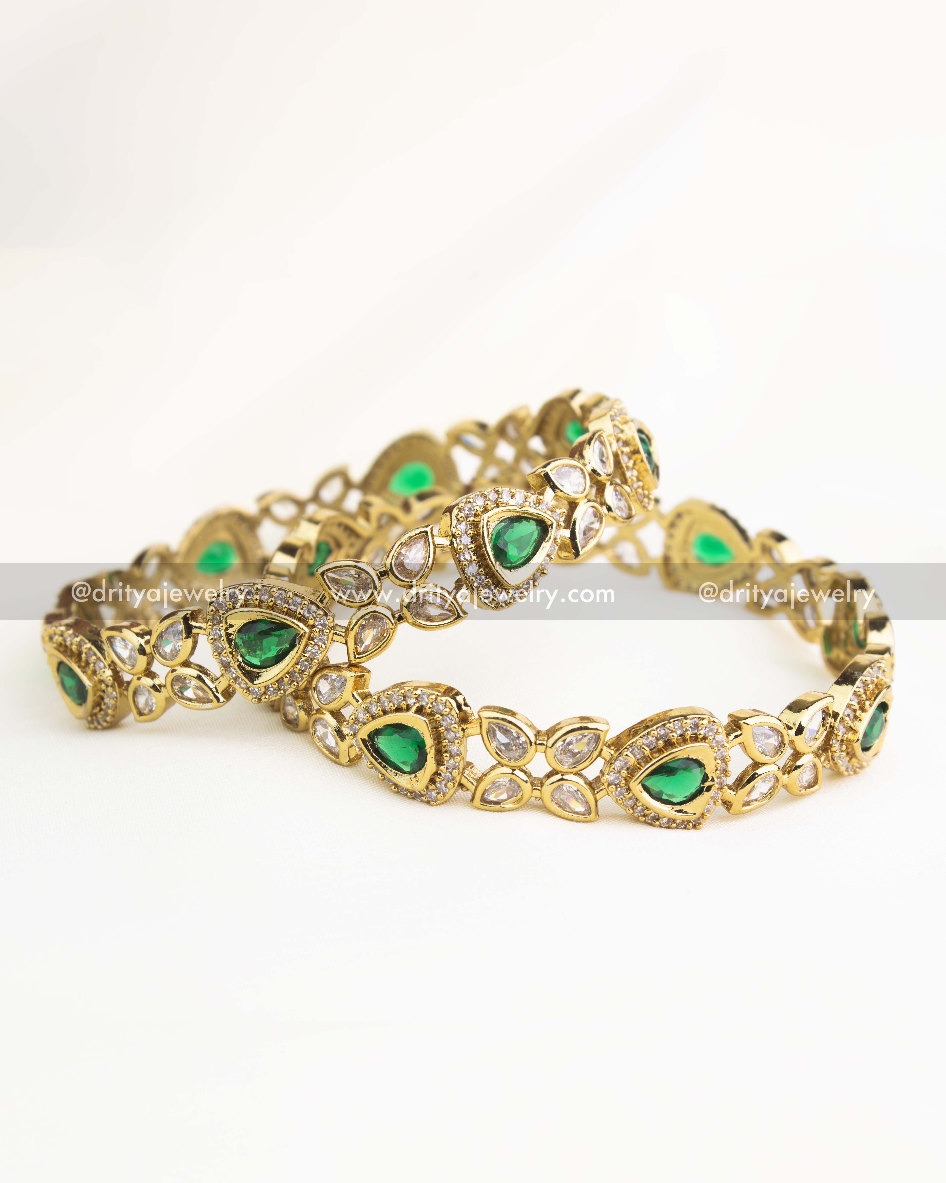 Emerald green AD stone Victorian bangles with gold polish and teardrop motifs.