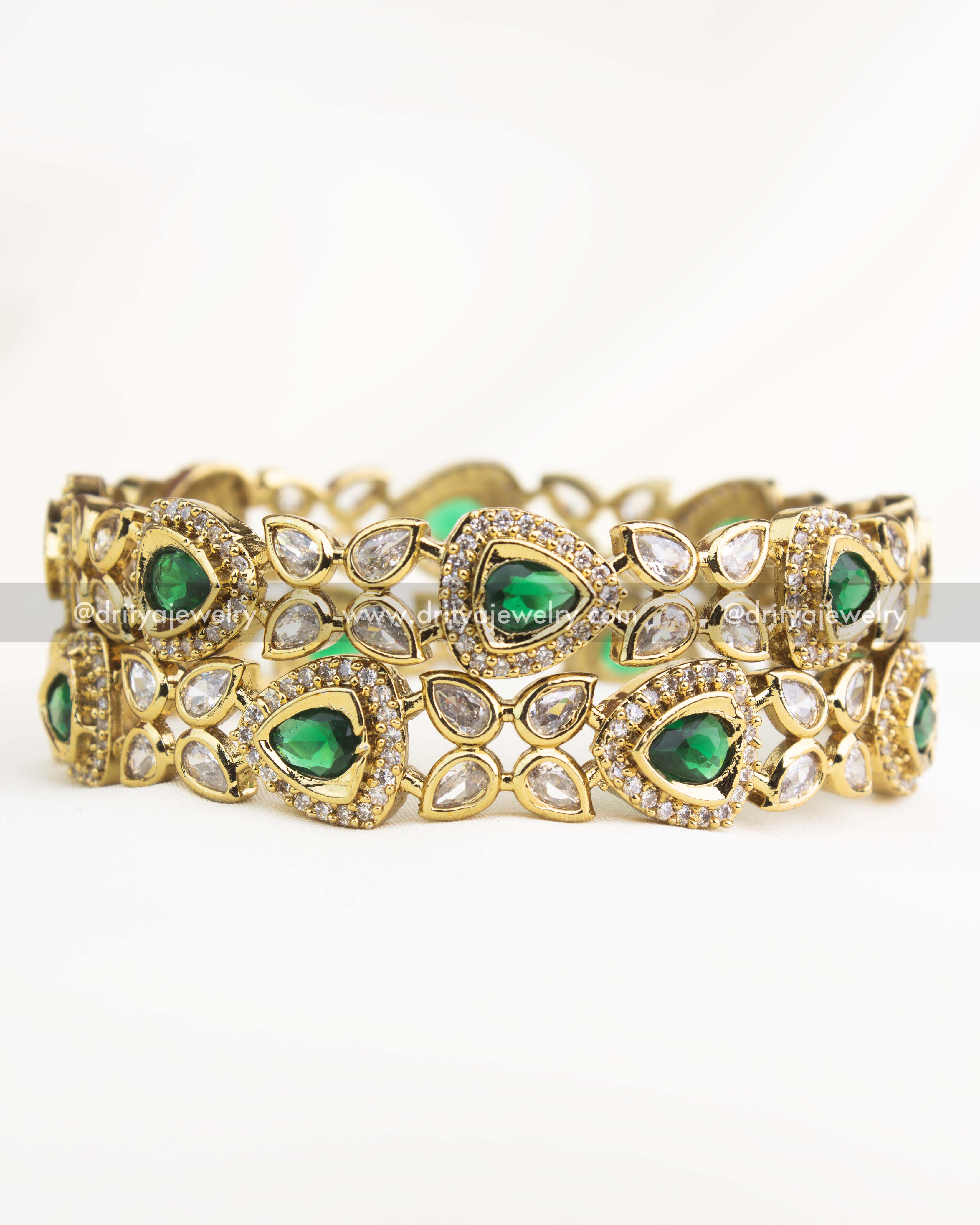 Emerald green AD stone Victorian bangles with gold polish and teardrop motifs.