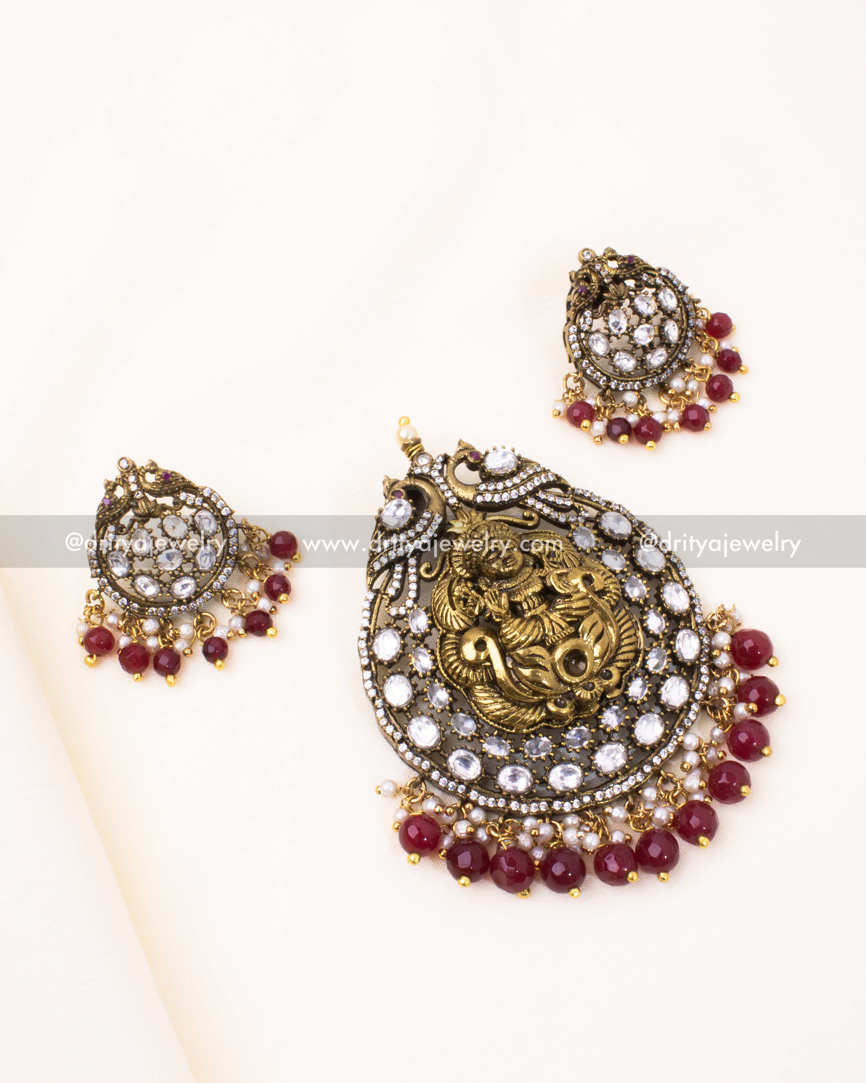 Elegant gold-plated Victorian pendant set featuring Lakshmi Devi motif, Kundan embellishments, and red crystal beads.