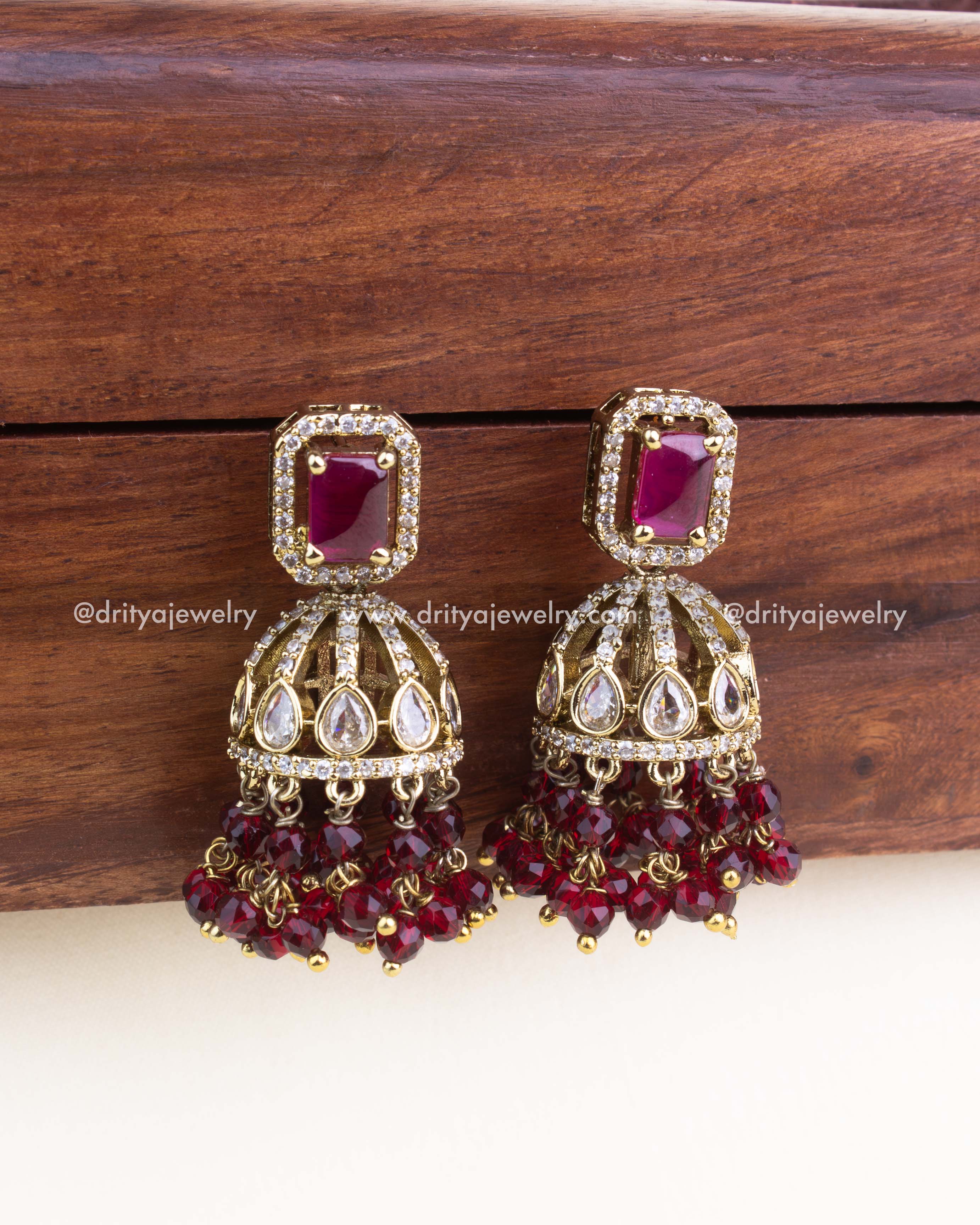 Pair of Victorian-style jhumka earrings with ruby red stones and bead clusters.