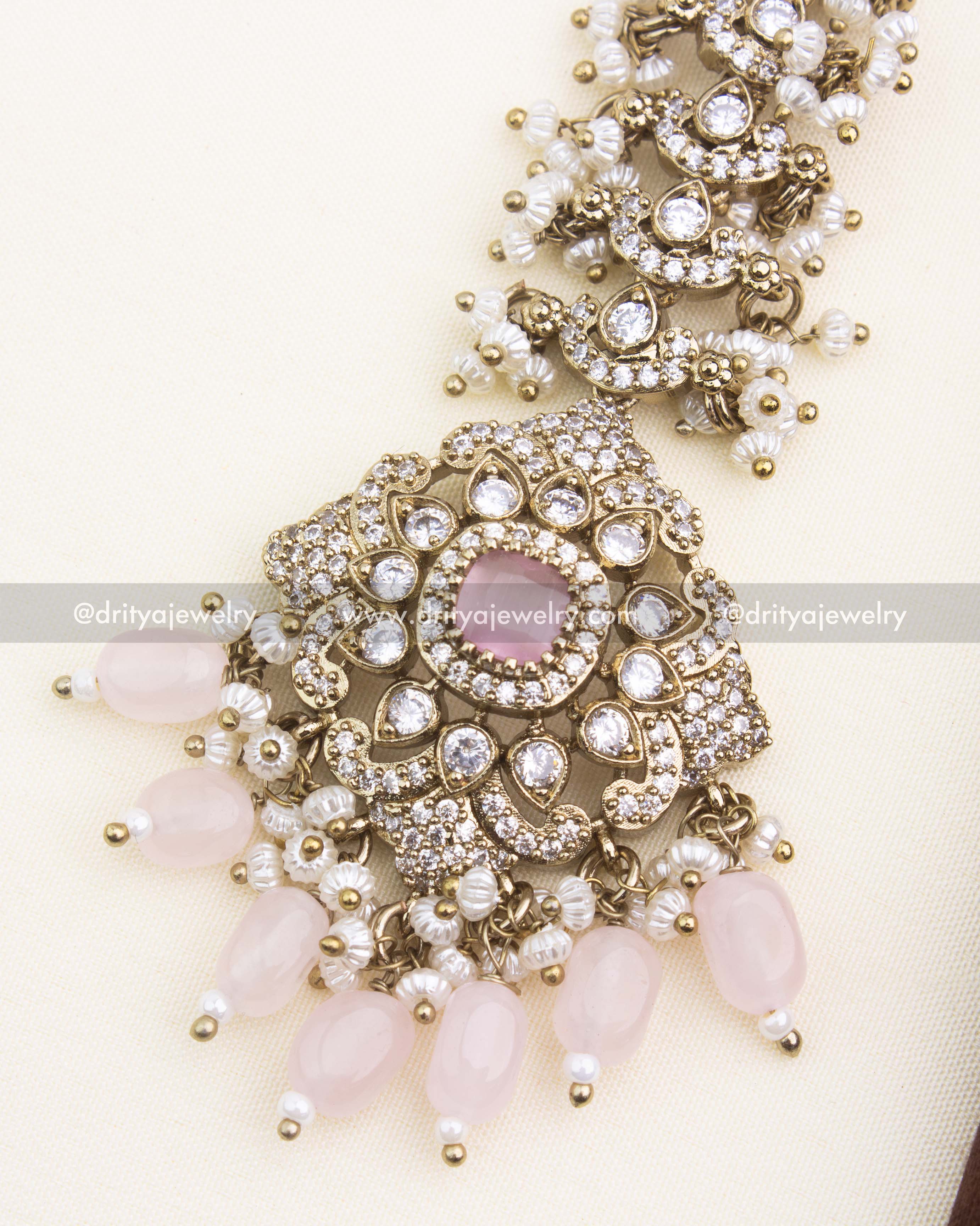 Close-up of blush pink Victorian maang tikka featuring CZ stones and soft pastel drops.