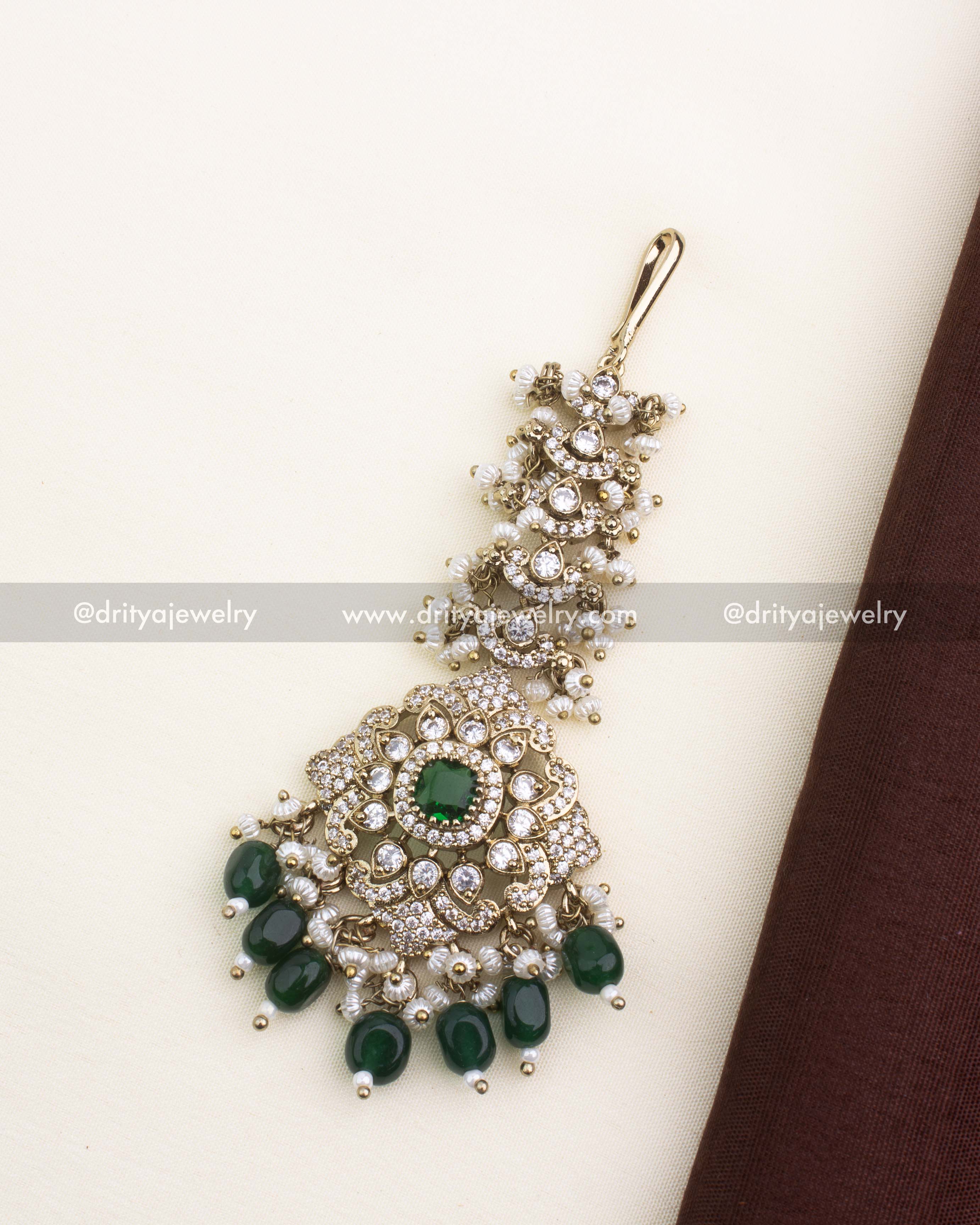Gold Victorian maang tikka with emerald green stones, CZ detailing, and pearl clusters.