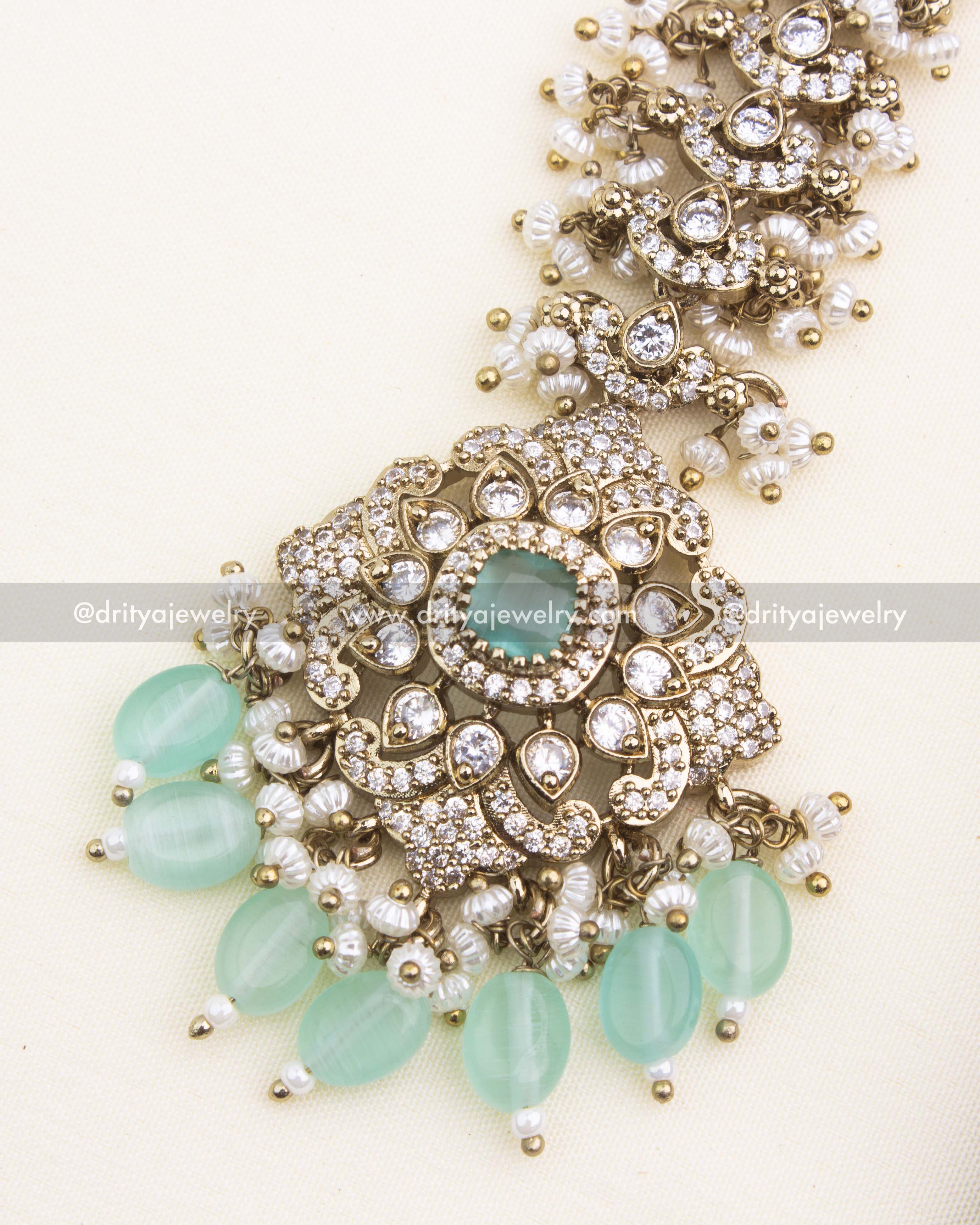 Close-up of mint green Victorian maang tikka with shimmering CZ stones and pearl drops.
