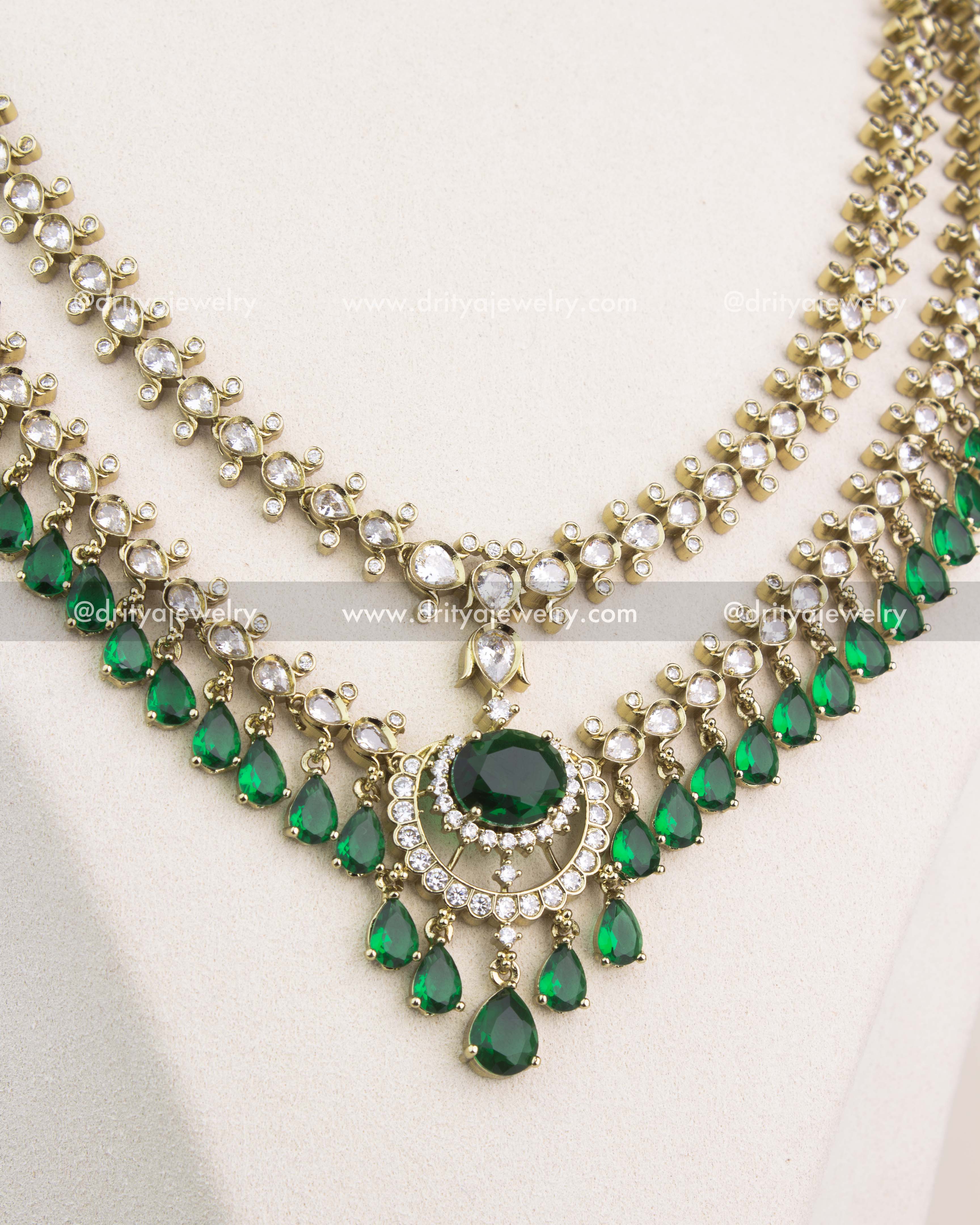 Detailed view of central emerald stone pendant surrounded by CZ embellishments in Victorian polish.