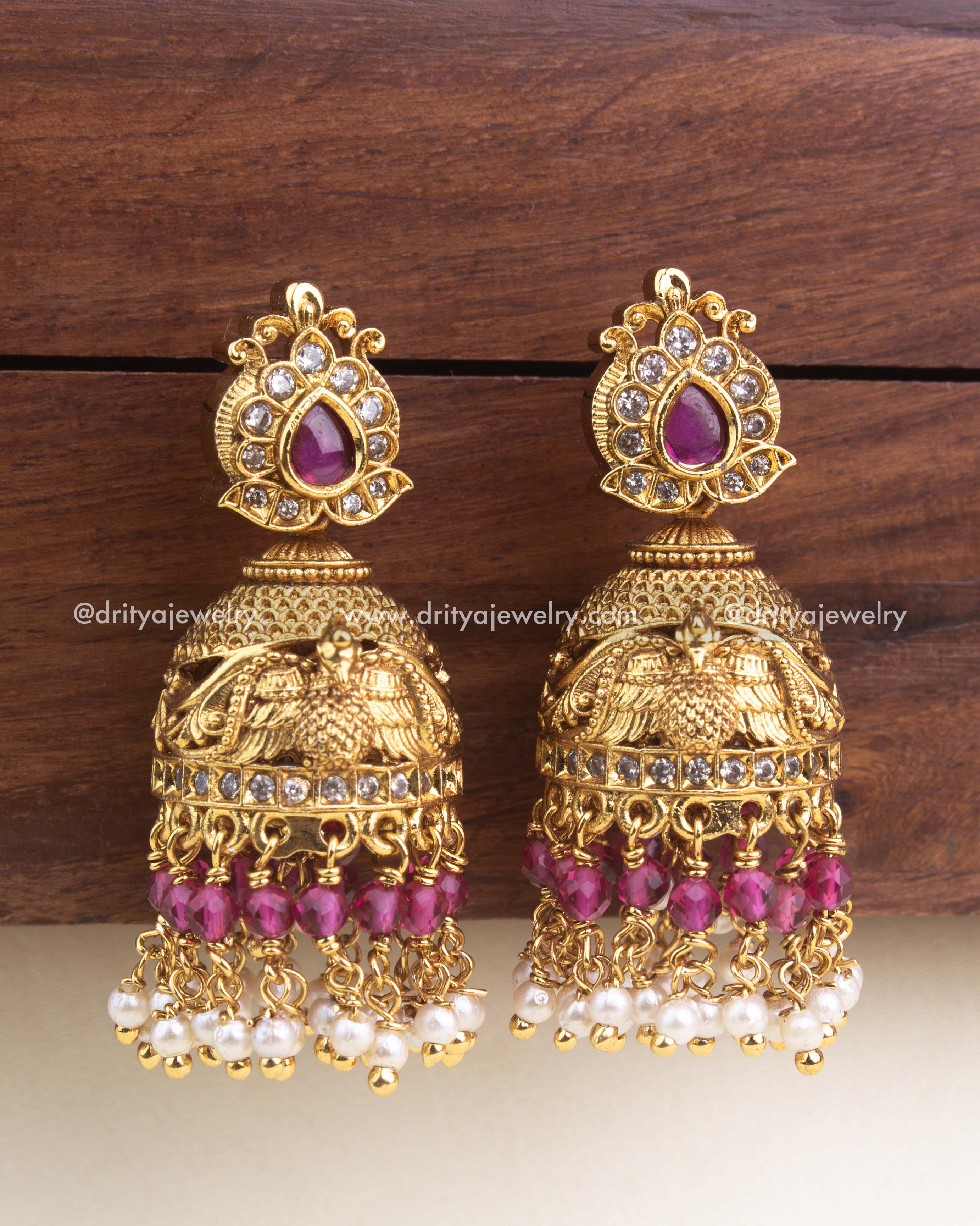 Premium antique jhumka featuring ruby tear-drop stone, gold detailing, and dual-layer bead hangings.