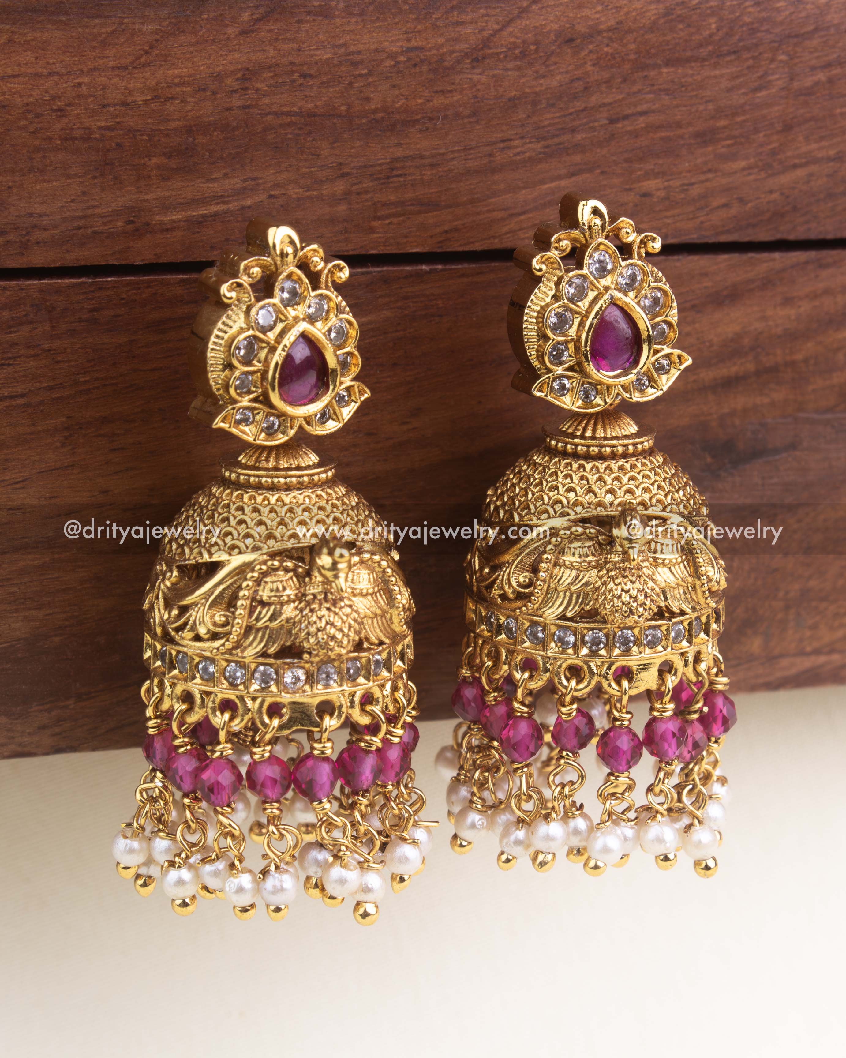 Antique-style jhumka with ruby red stones, carved bird design, red beads, and pearl danglers.