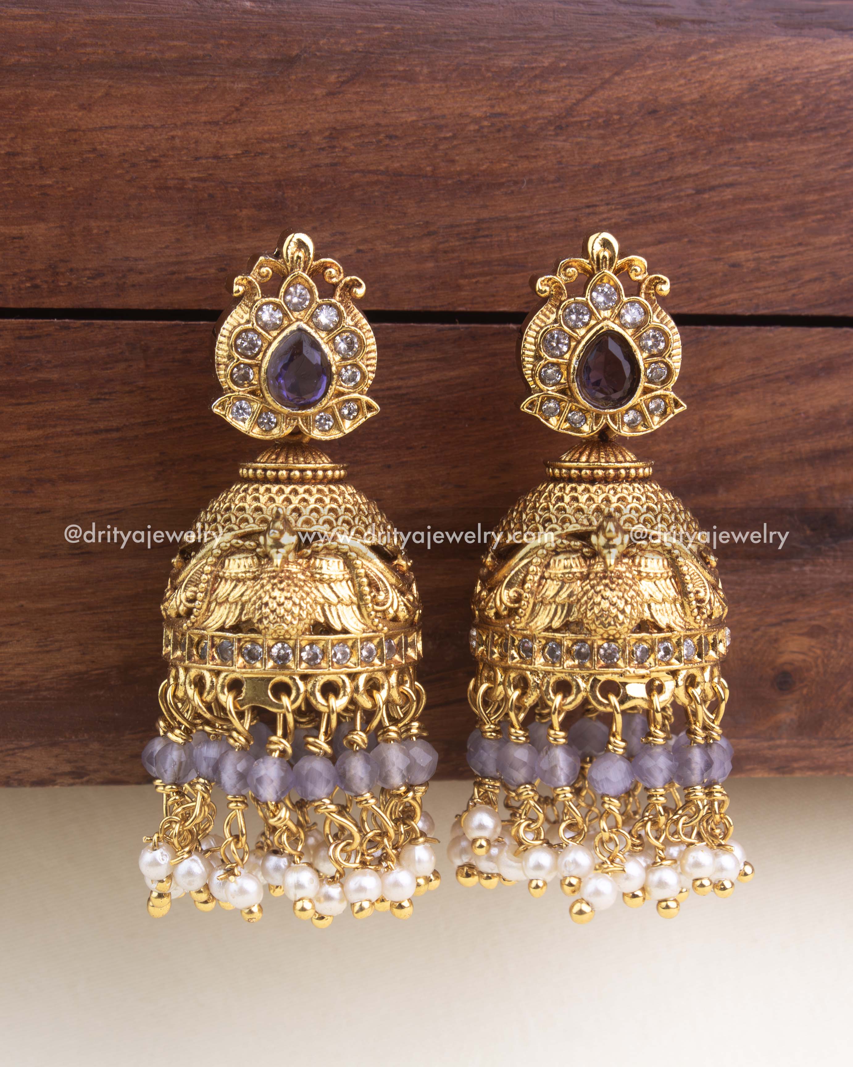 Premium antique jhumka with purple stones, engraved bird motifs, and pearl + lilac bead clusters.