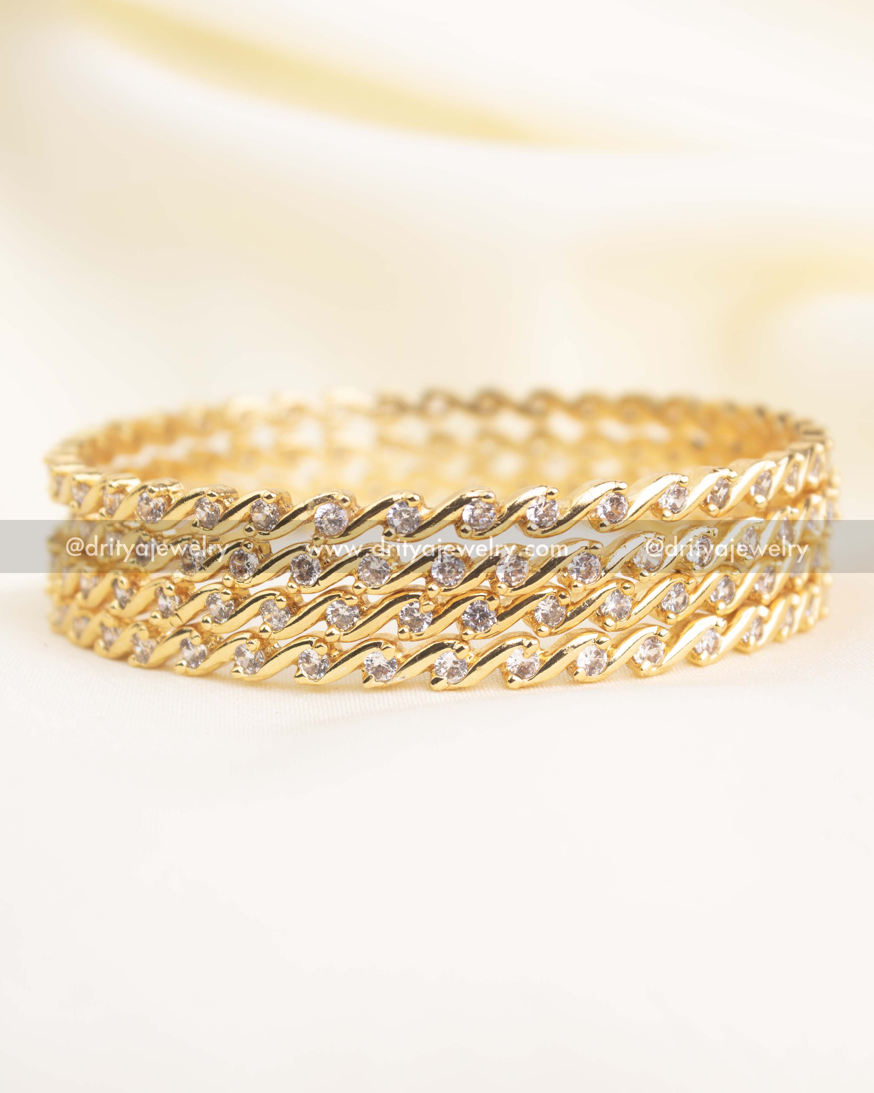 Gold-polish slim bangles with wave-pattern CZ stones arranged in a diamond-alike style.