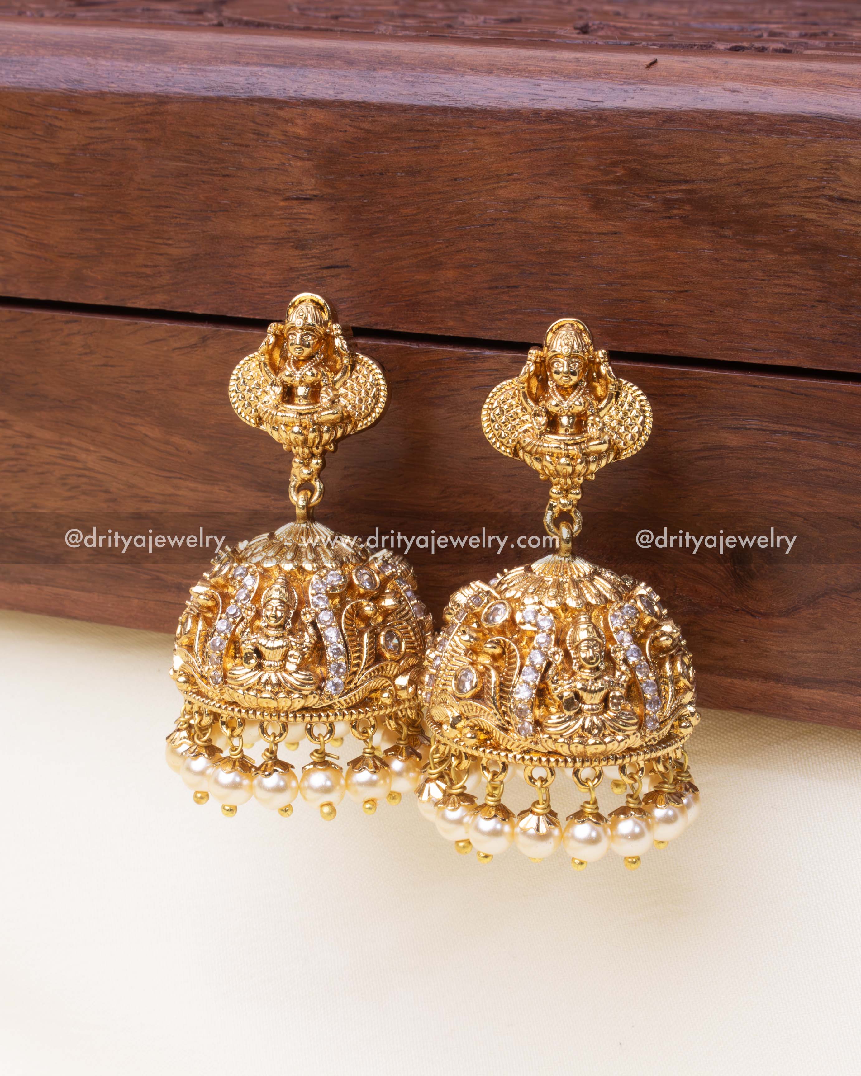 Dome-shaped jhumkas adorned with white CZ stones and delicate pearl hangings.