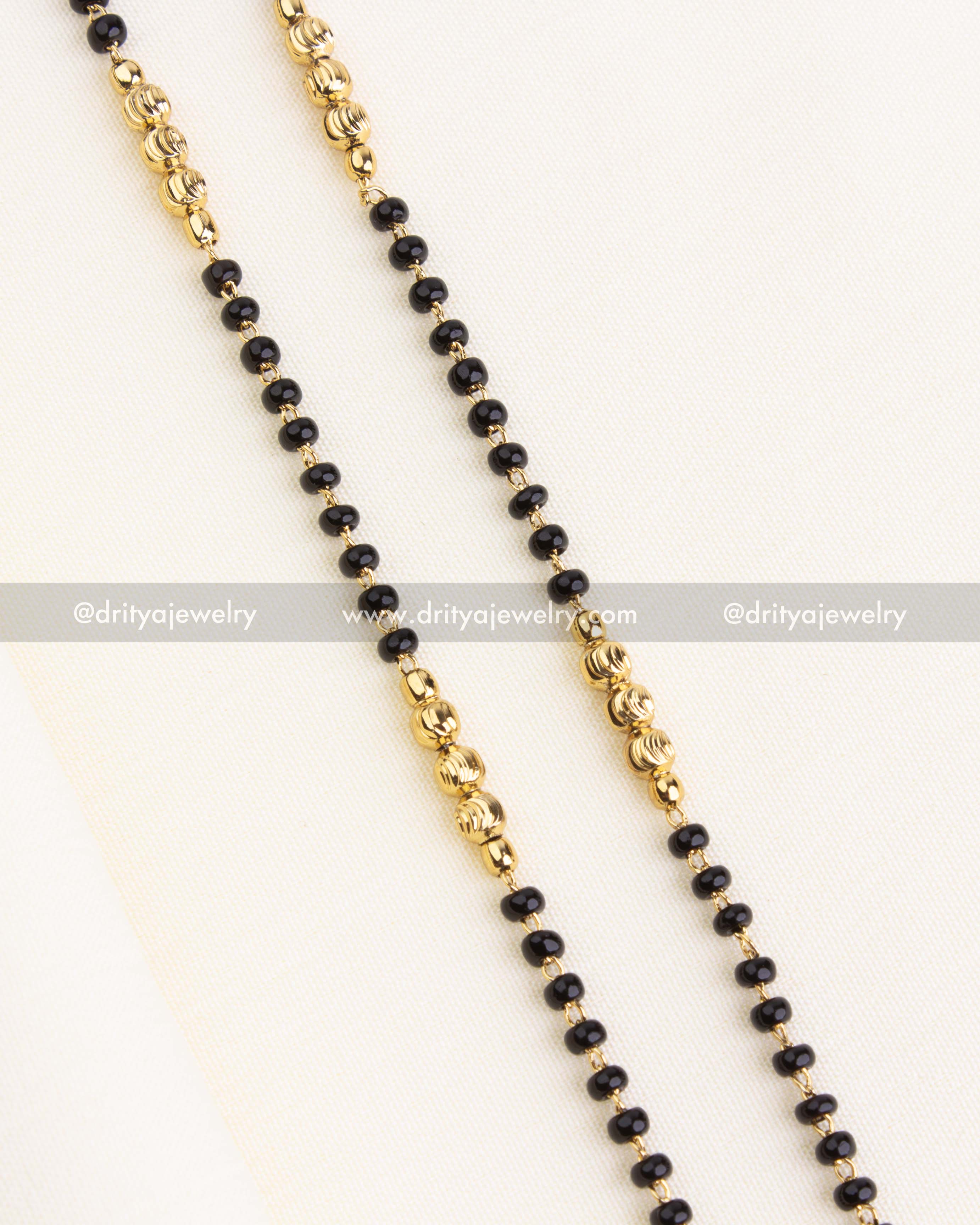 Close-up of dual-strand black beads necklace with textured gold beads and traditional design.