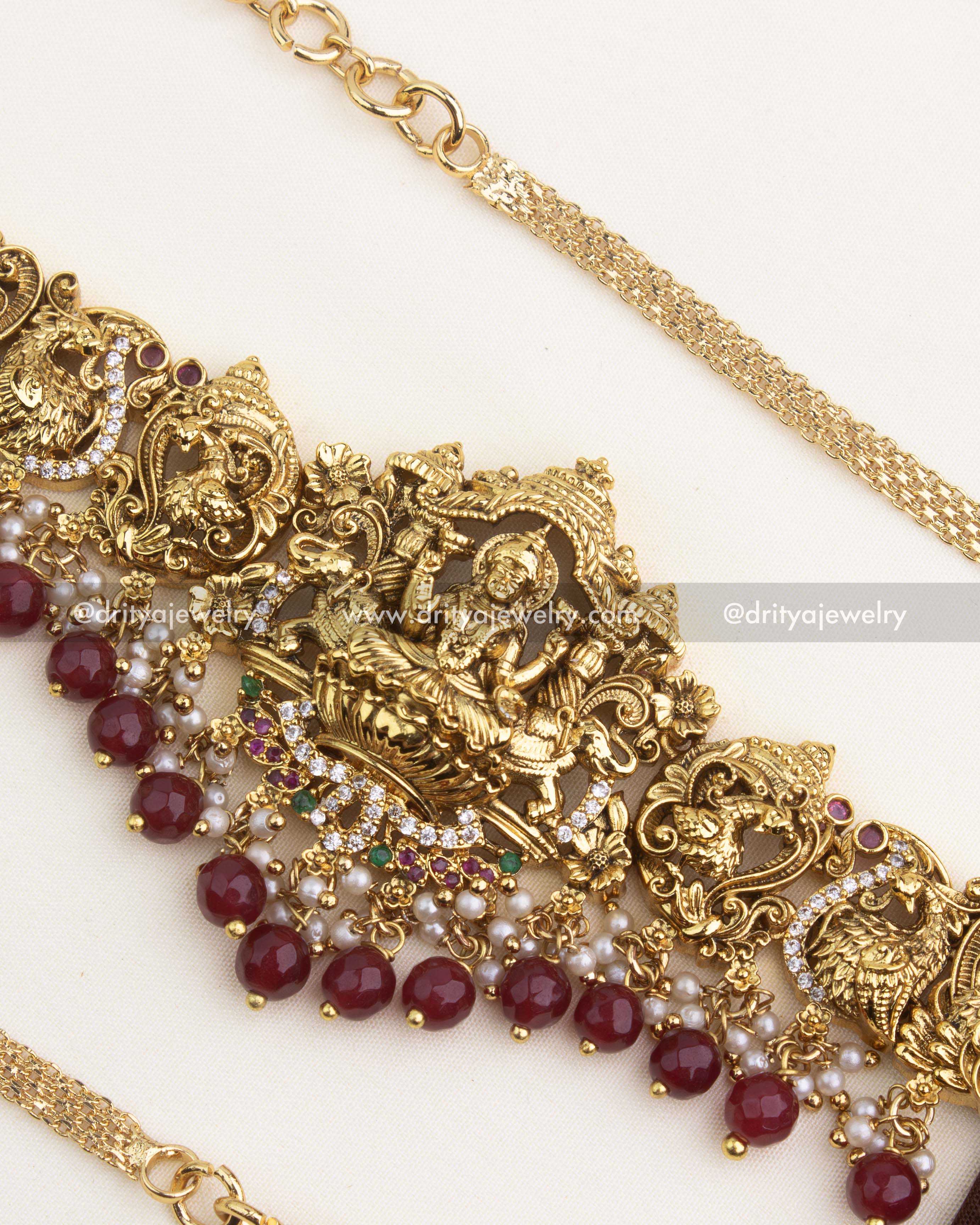 Intricate Lakshmi temple pendant adorned with CZ stones, pearls, and ruby red beads.