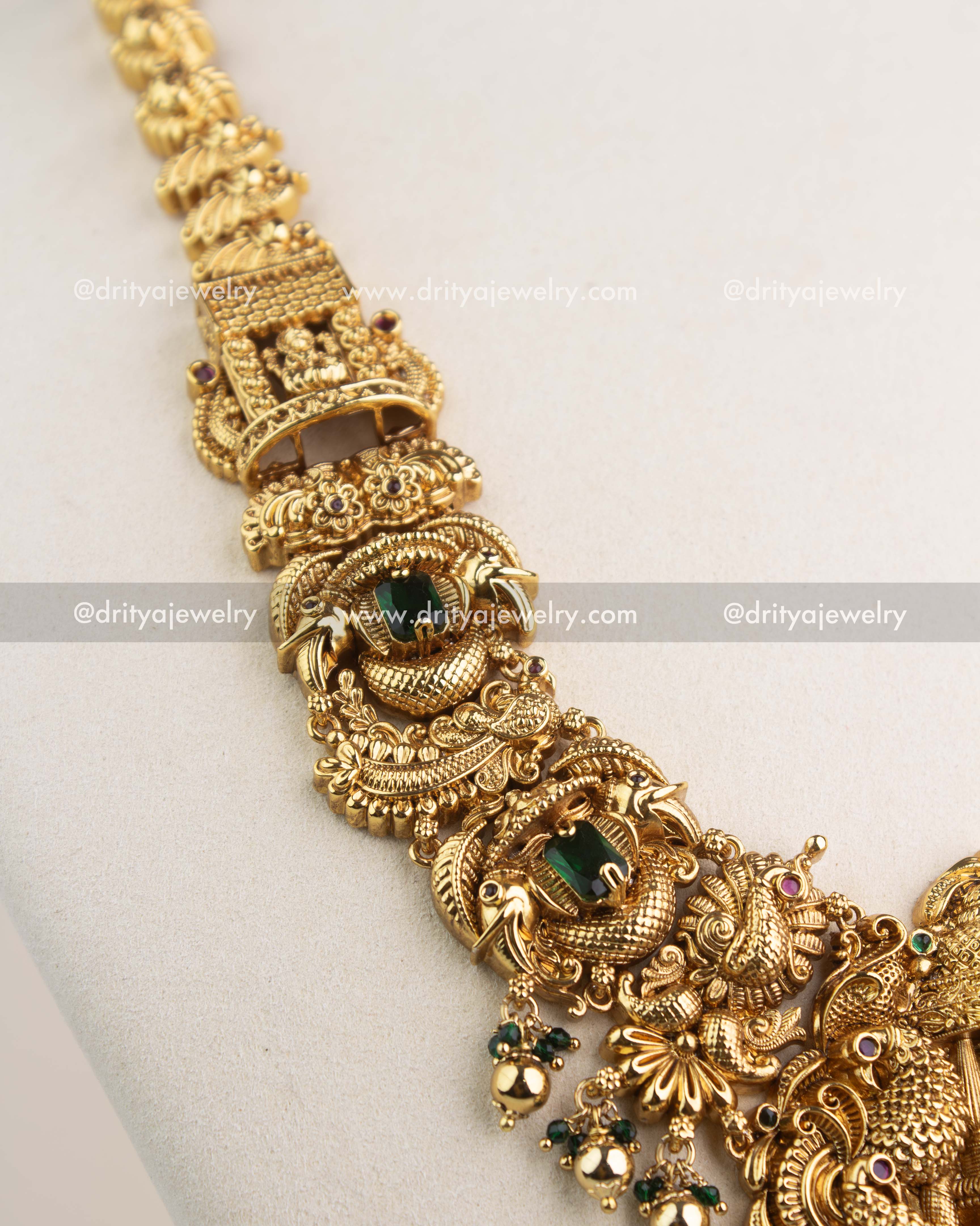 Close-up of intricate Nakshi carvings, peacock motifs, and green stone detailing in temple necklace.