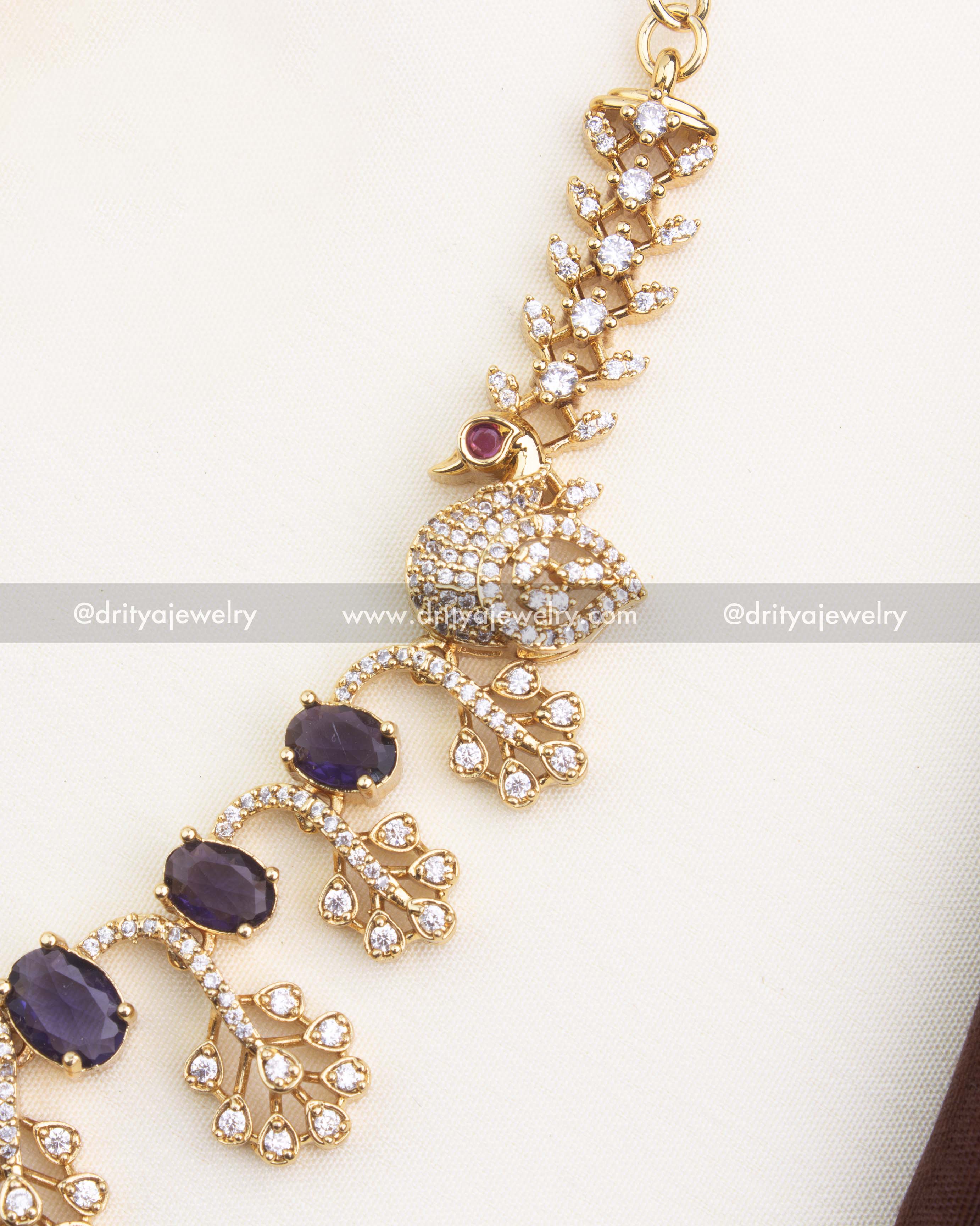 Close-up of purple oval CZ stones with AD leaf clusters and peacock detailing.