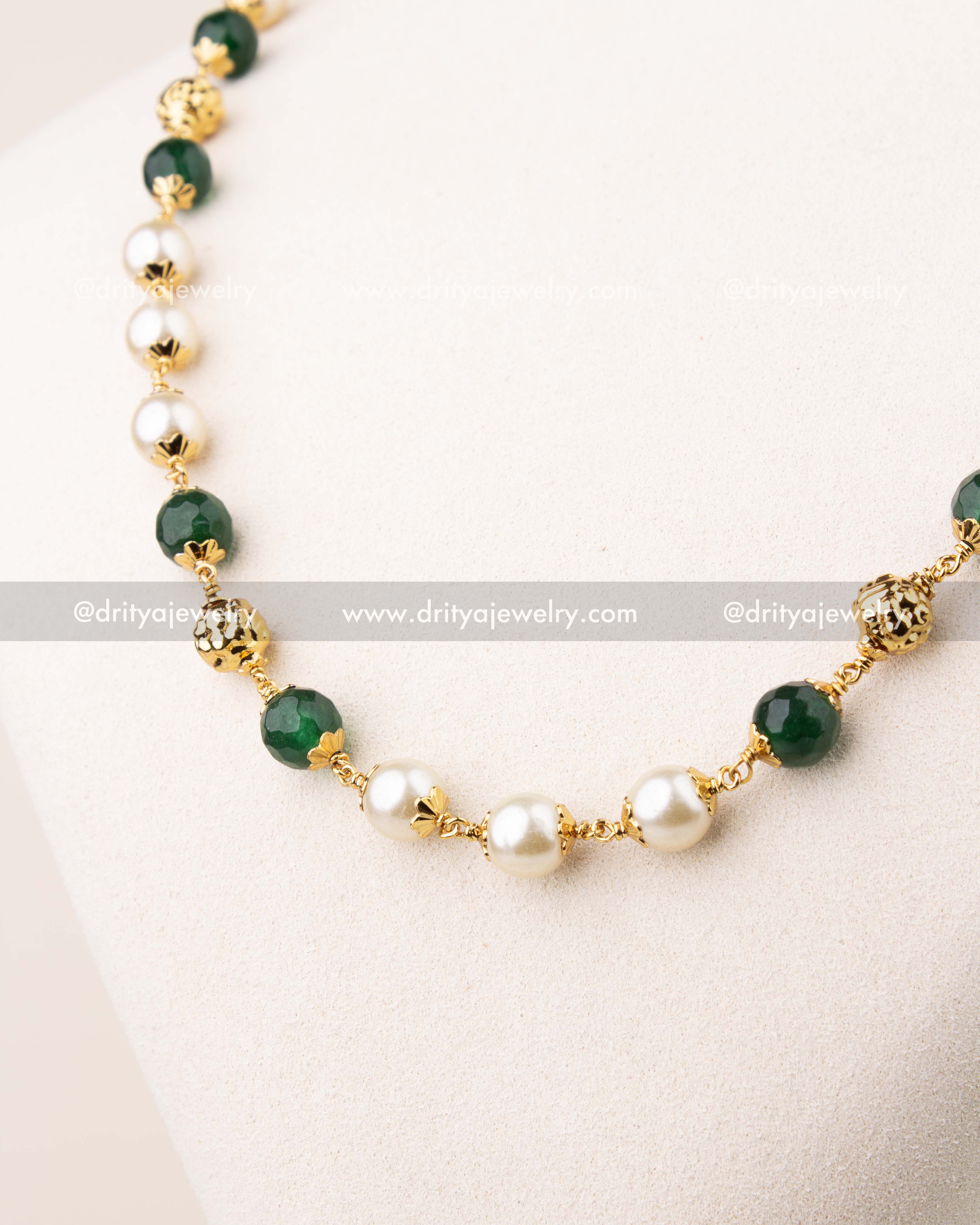 Close-up of pearl and emerald beads mala with gold-toned spacer detailing