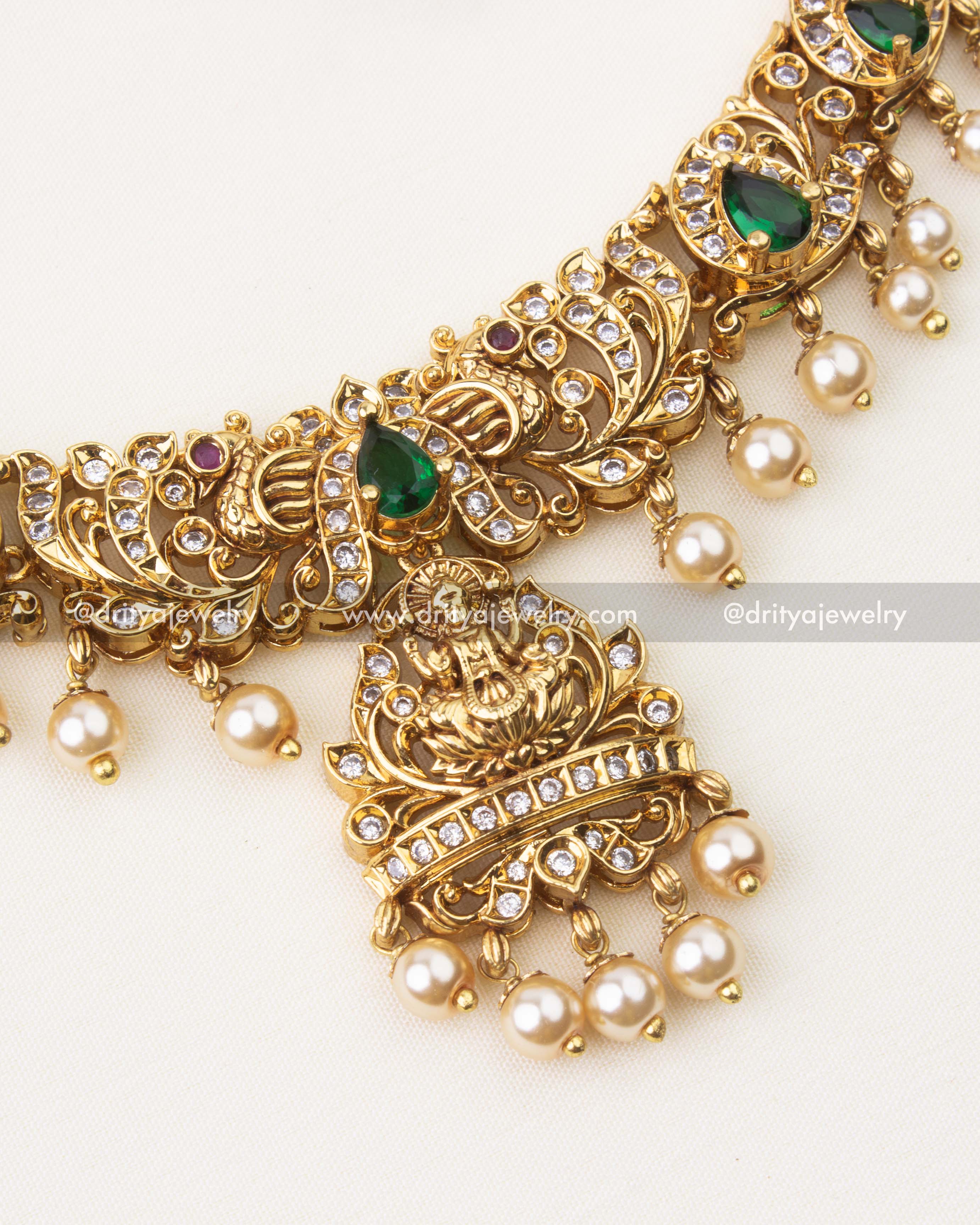 Close-up of Nakshi temple necklace featuring emerald green stones, CZ accents and pearl hangings