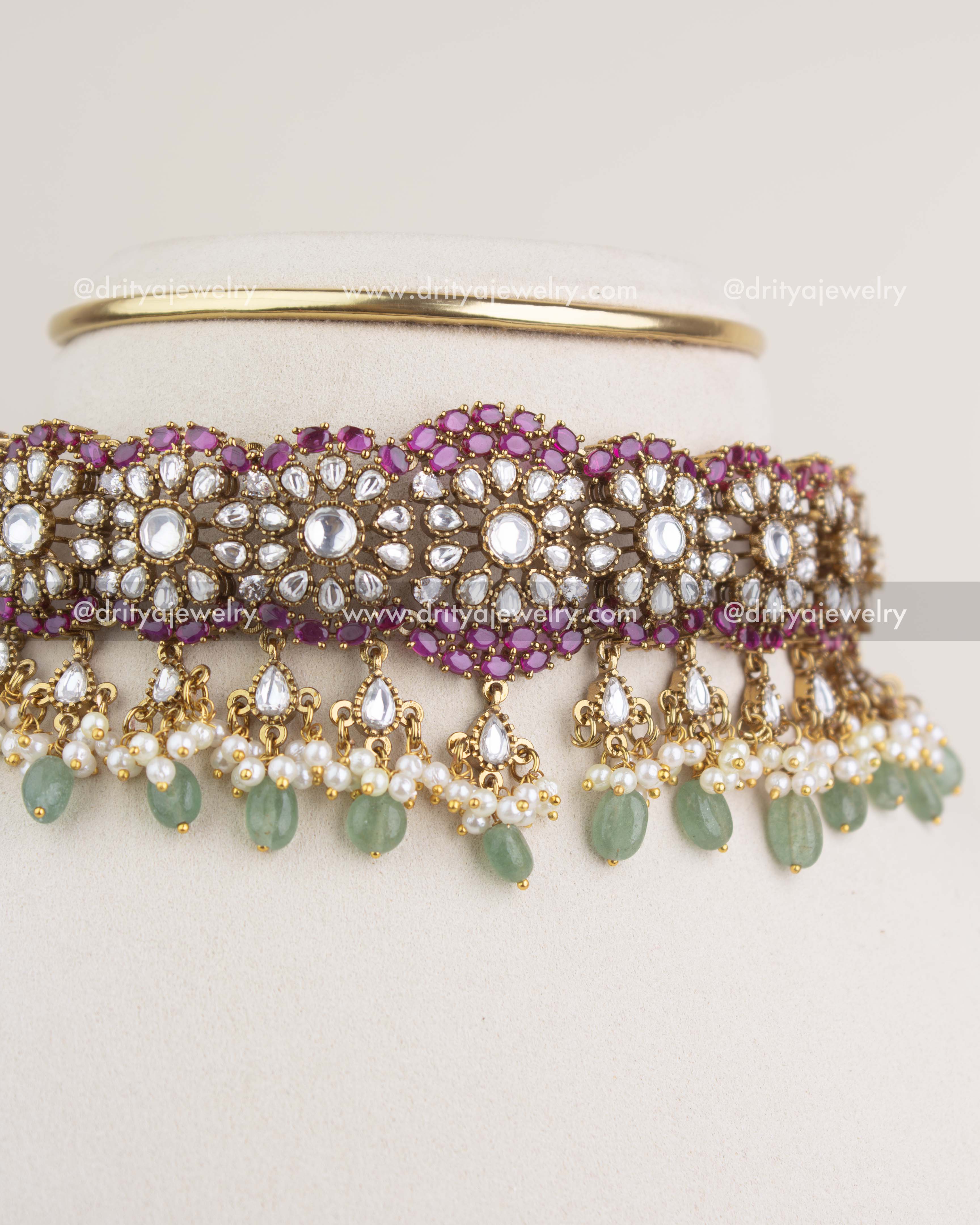 Close-up view showing polki kundan floral detailing, ruby stones, pearls, and green beads on the choker.