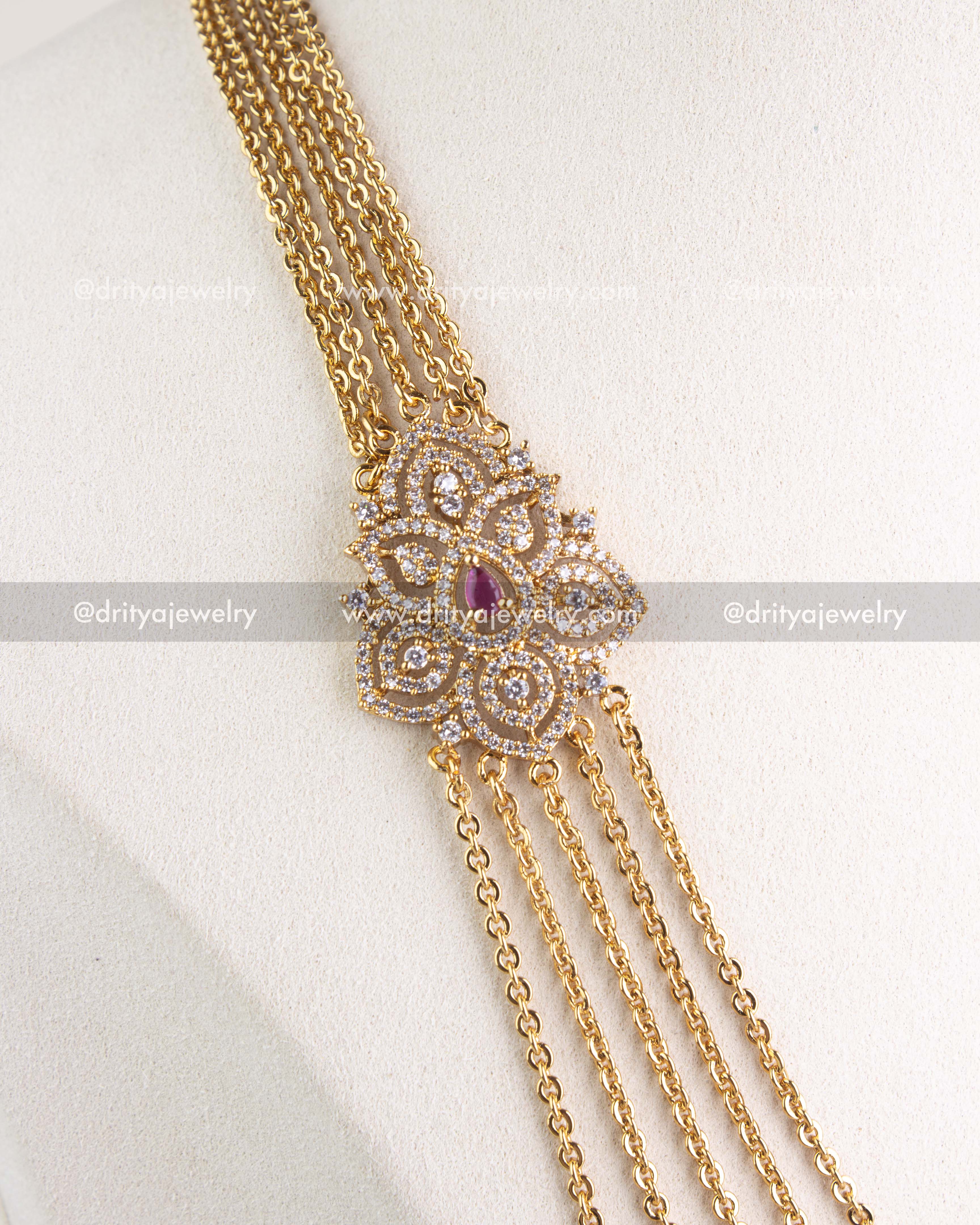 Close-up of layered chandrahaar necklace with CZ floral pendant and ruby red stone on mannequin