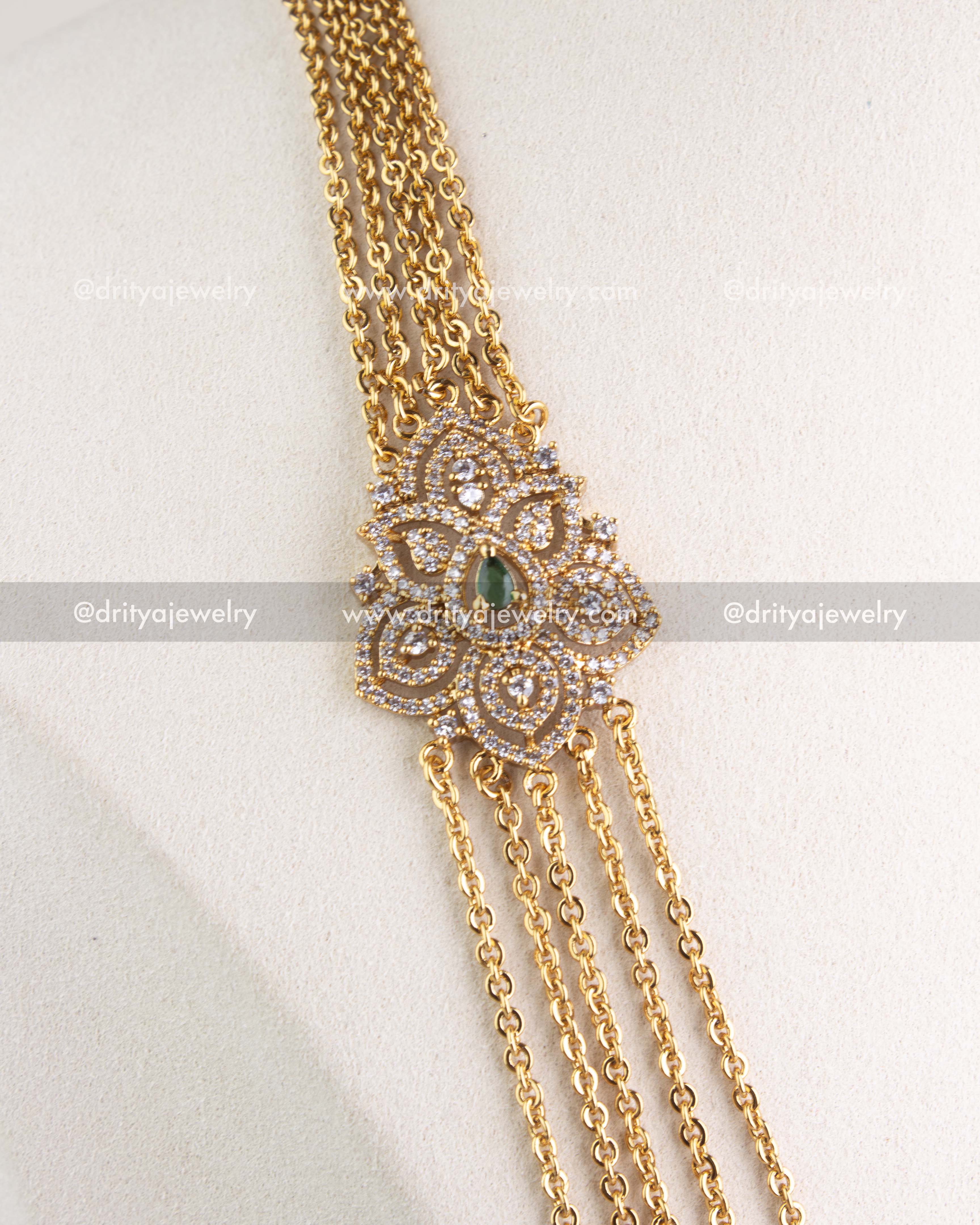 Close-up of layered gold-tone chandrahaar necklace with CZ and emerald green pendant, SKU 1120-G