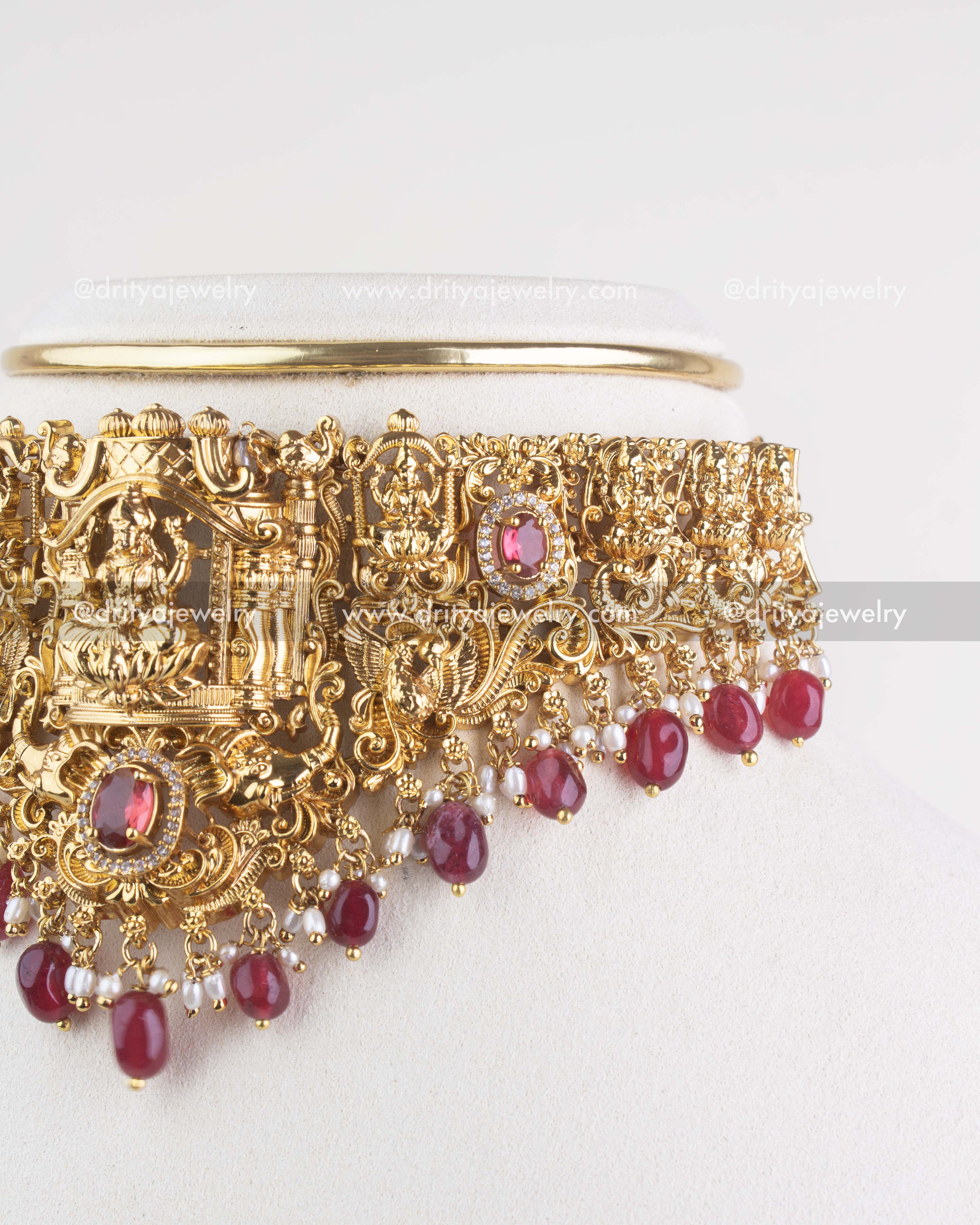 Side close-up of temple choker necklace showing deity motif, ruby stones, and ruby bead drops
