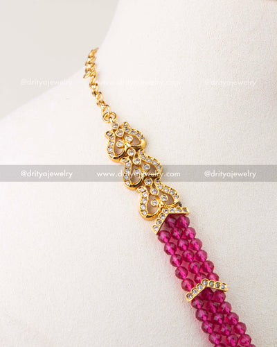 Back side detail of pink beaded necklace with gold-toned chain and stone-studded link.