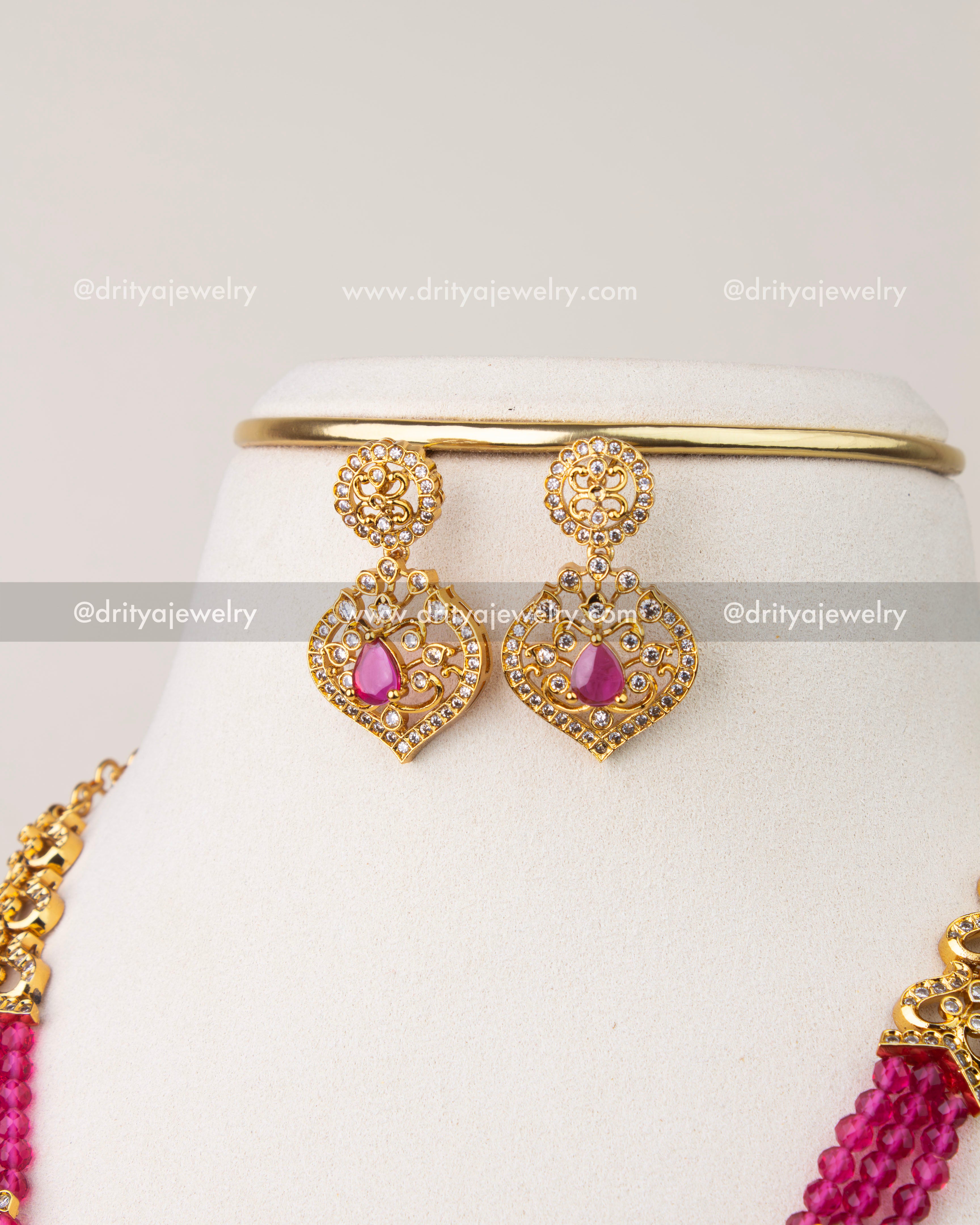 Front view of matching gold-toned earrings with pink center stones and crystal accents.