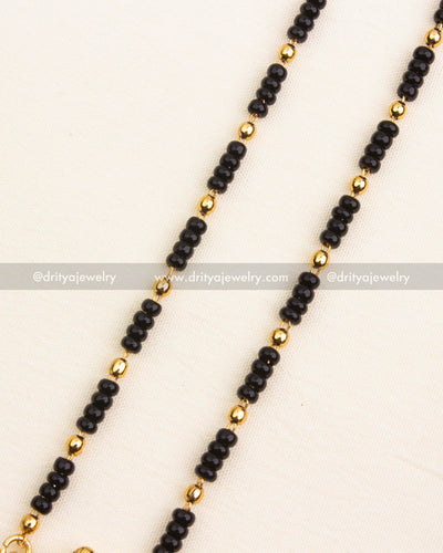 Detailed view of single-line black beads chain with golden bead separators, 18 inches long.