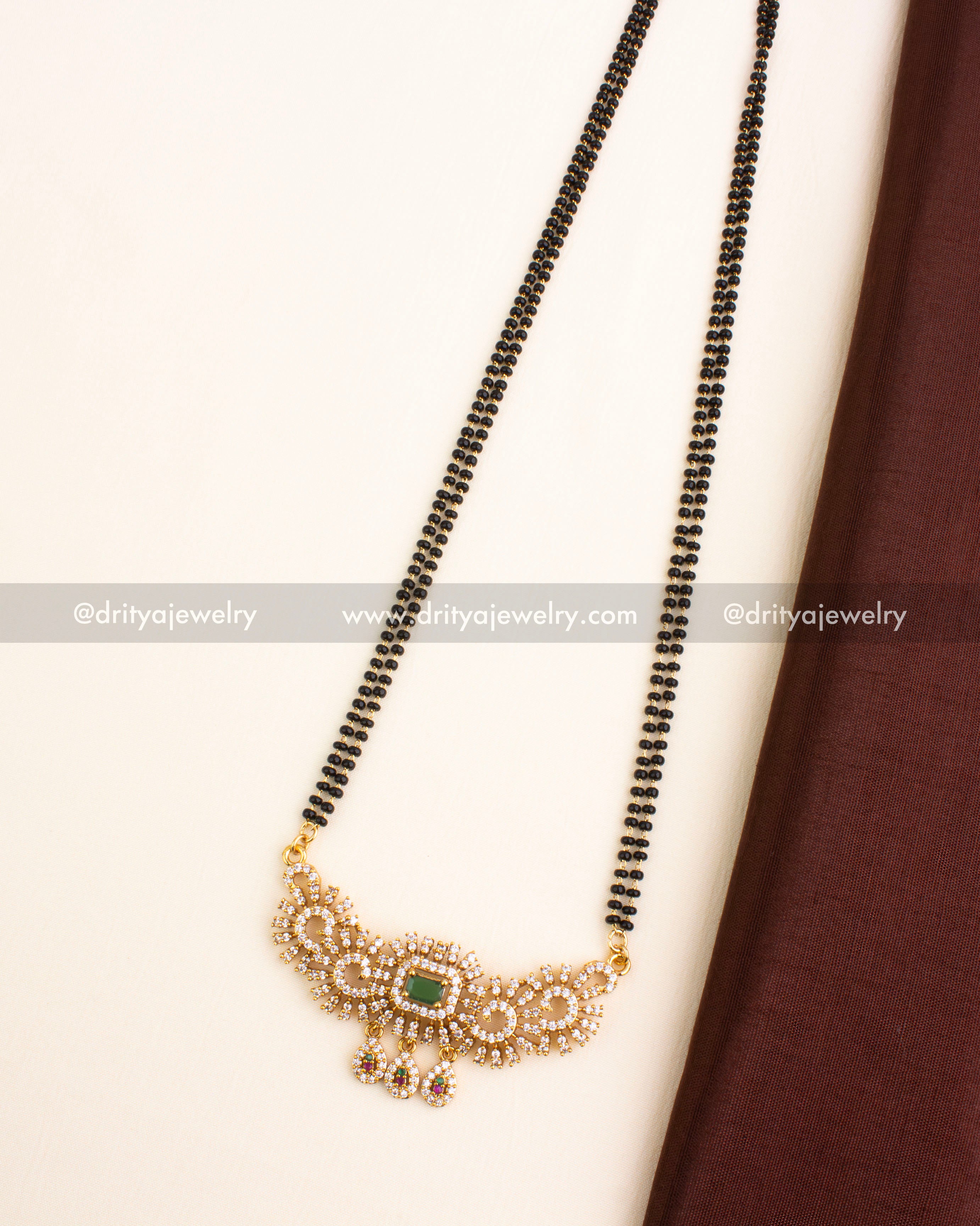 Gold-plated black beads necklace with green stone pendant and teardrop danglers