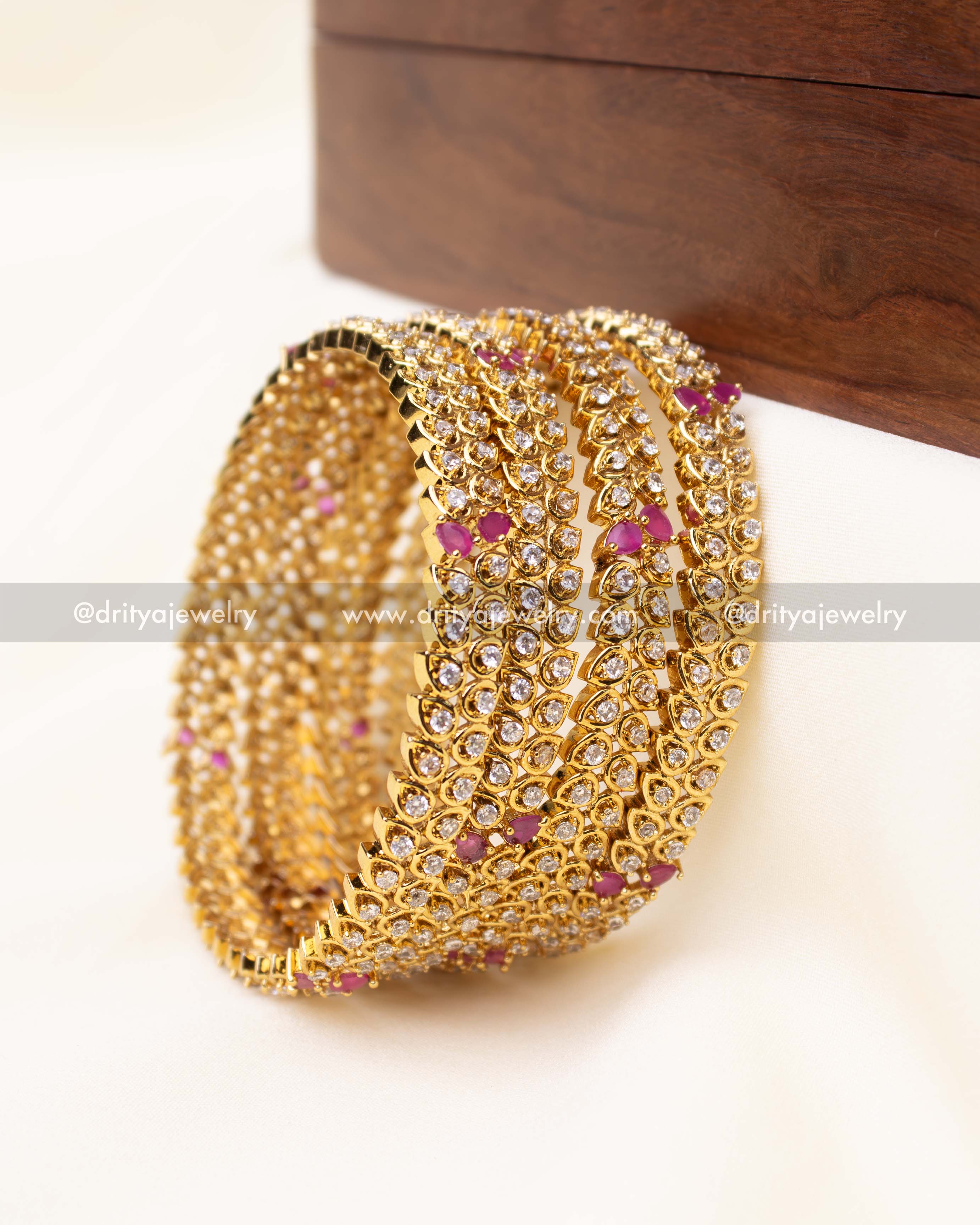 Detailed close-up of CZ-studded gold bangles with pink stone highlights.