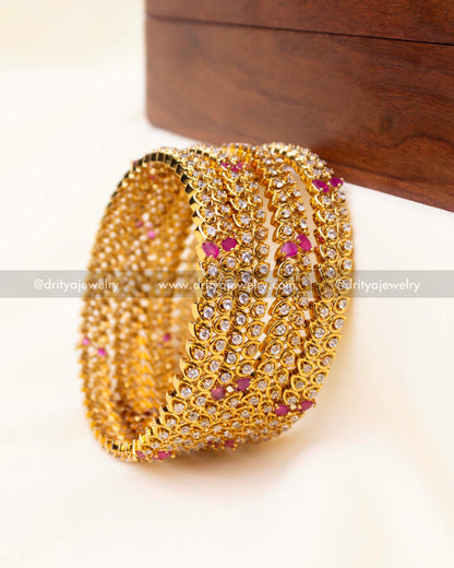 Detailed close-up of CZ-studded gold bangles with pink stone highlights.