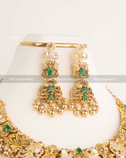 Pair of antique danglers designed with intricate polki kundan work, green teardrop stones, pearls, and golden bead hangings.
