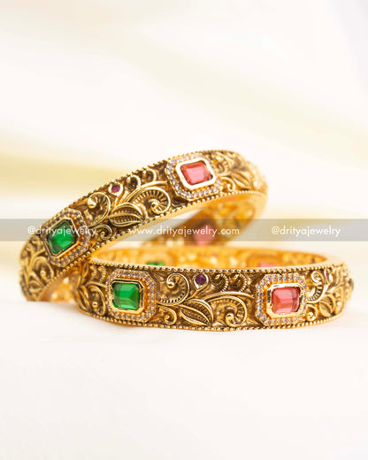 Premium antique gold bangles with floral nakshi engraving and rectangular ruby-pink and green stones.