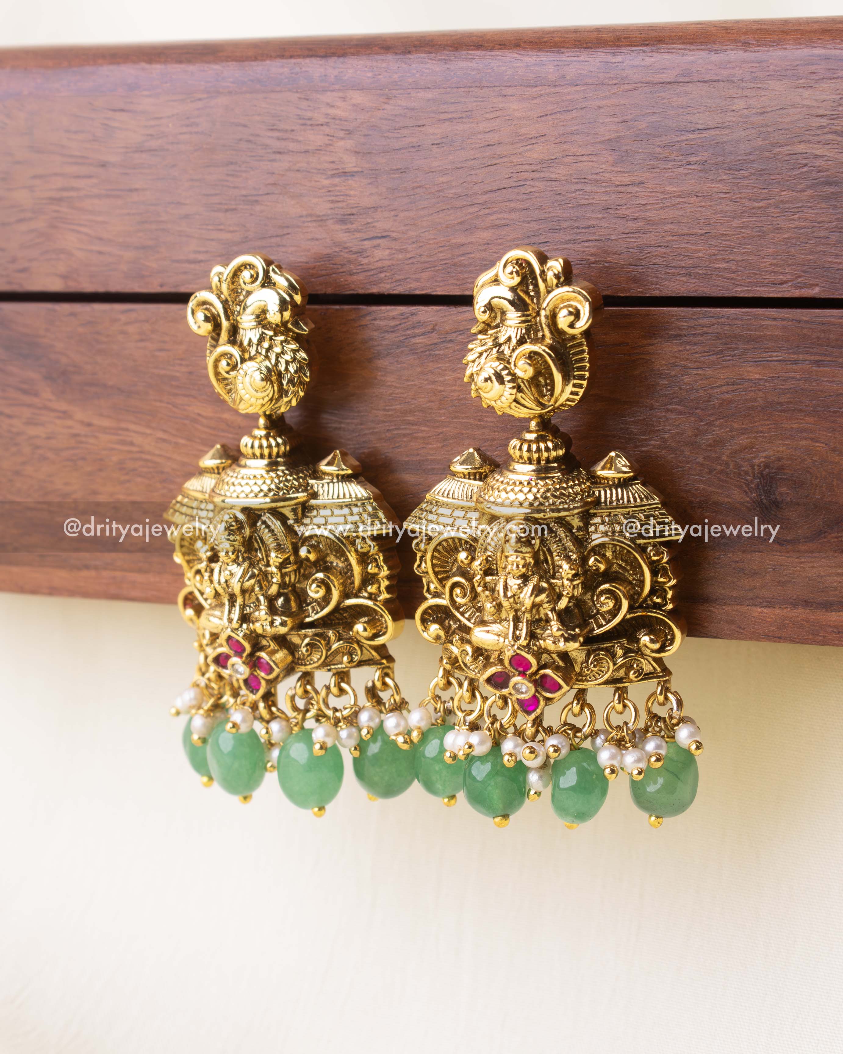 Detailed view of mint green drop earrings featuring Goddess Lakshmi in antique gold finish.