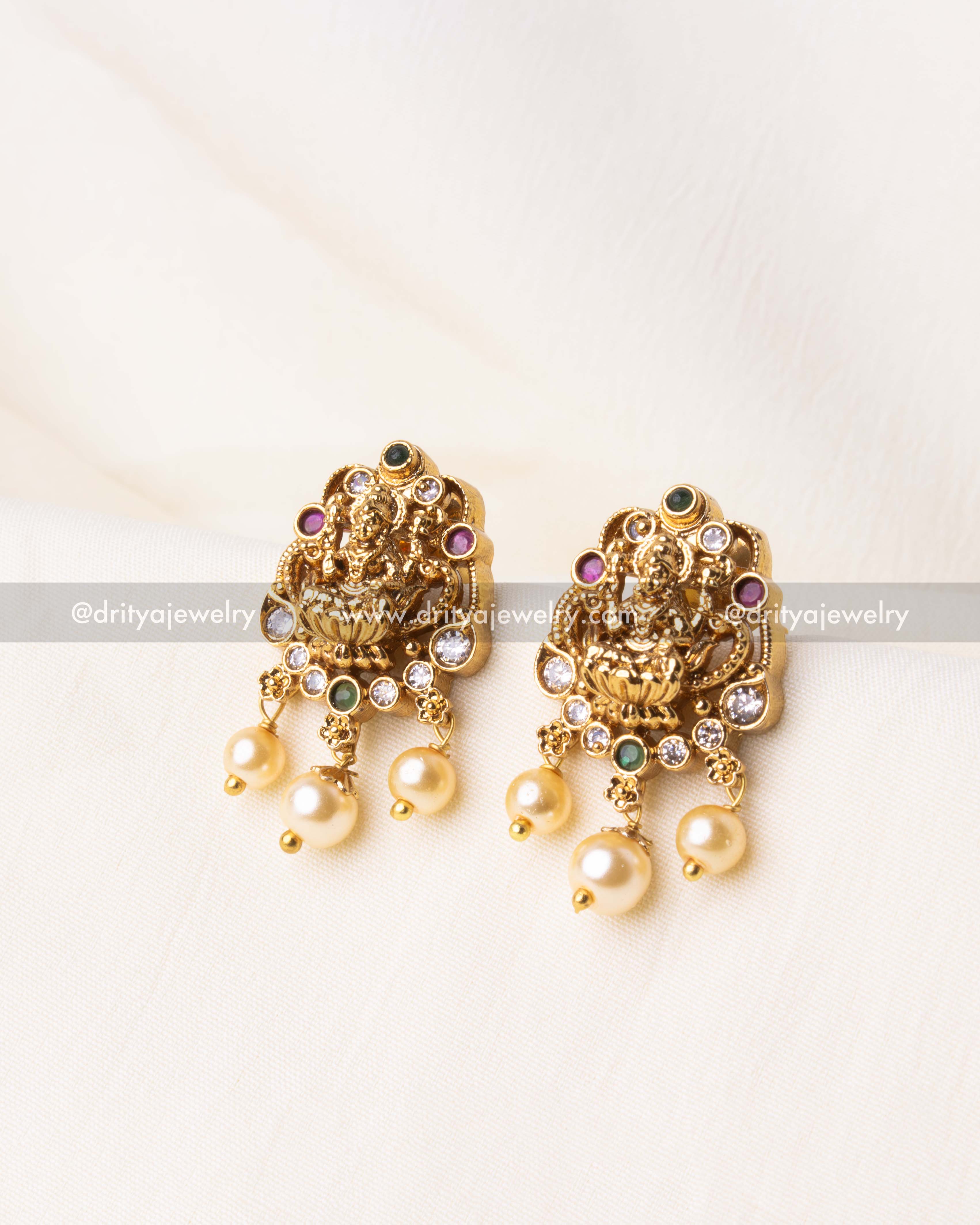 Exquisite Nakshi stud earrings featuring an antique gold finish, Lakshmi motif, and pearl drops.