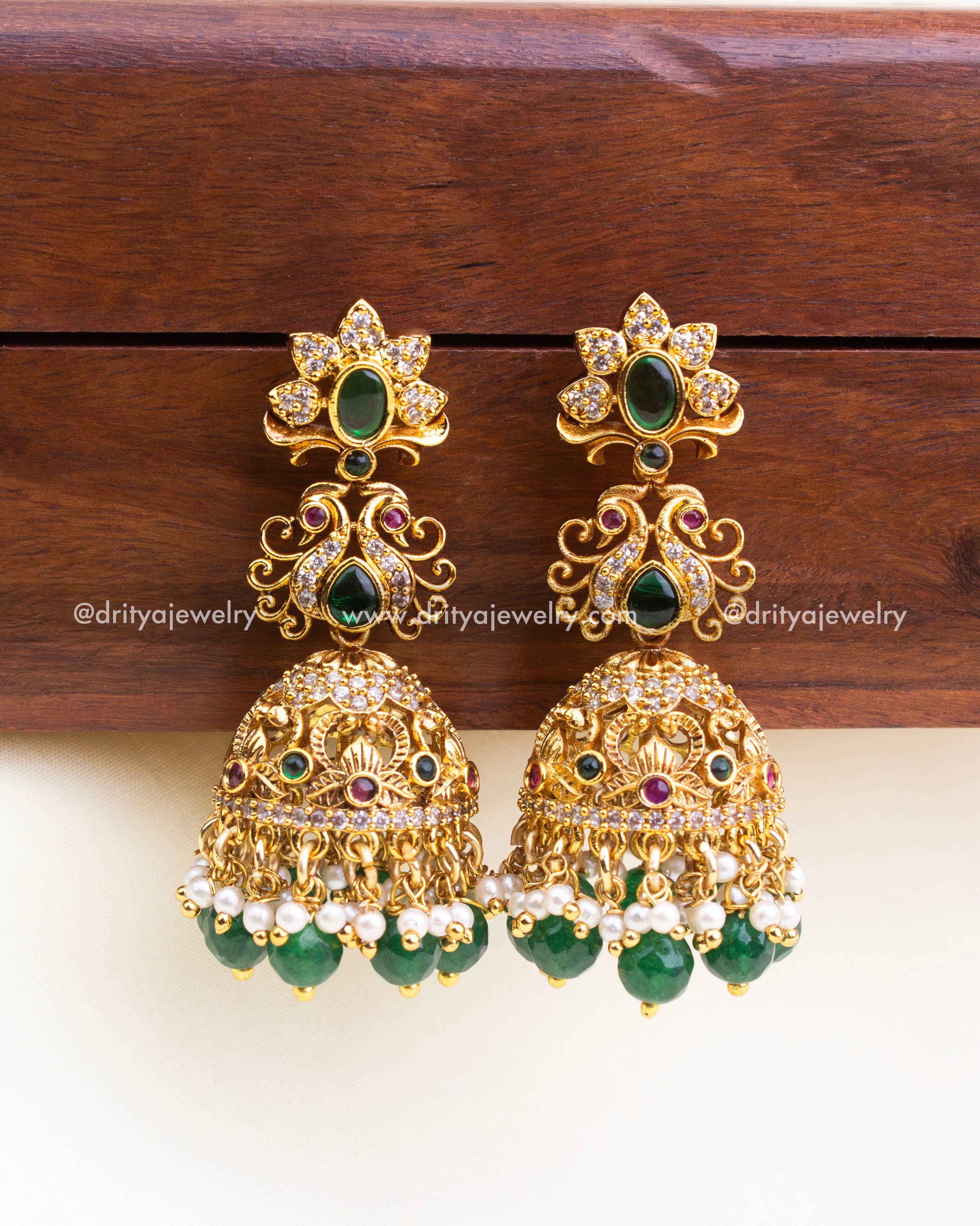 Temple-style jhumkas with antique gold finish, green bead drops, and pearl accents – no god idol.
