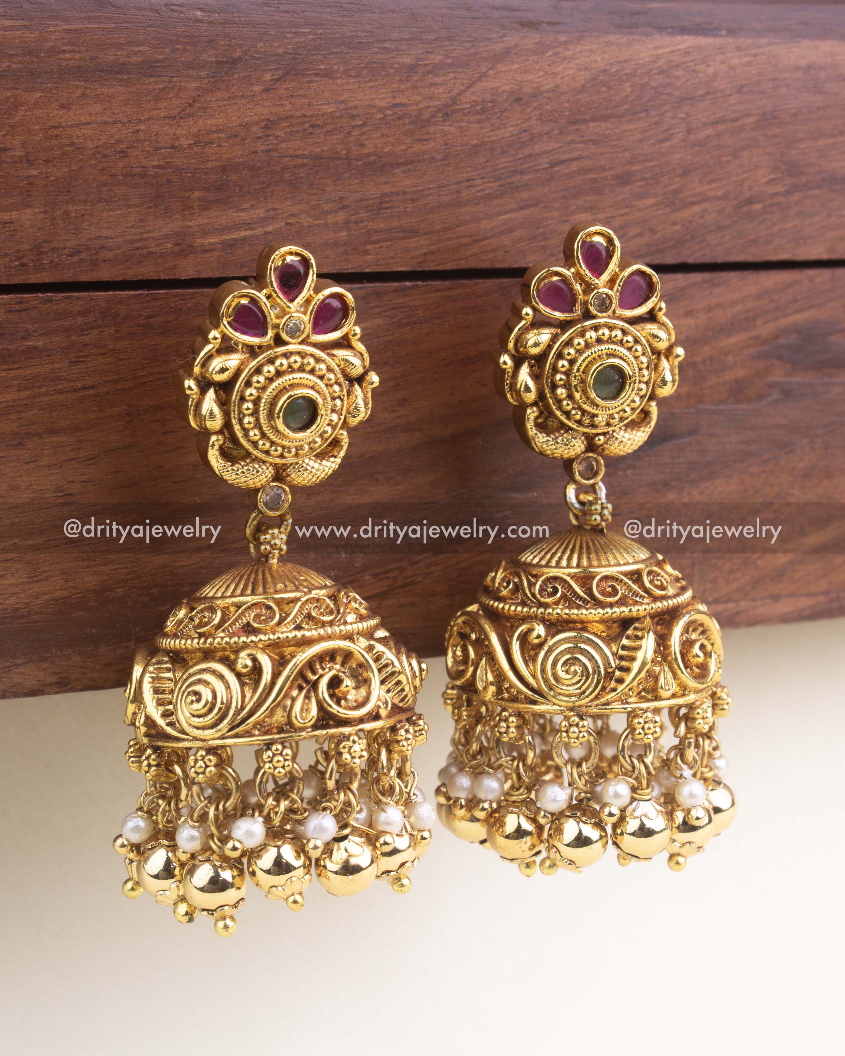 Close-up showing embossed swirl patterns on the jhumka dome, kemp stones on stud, and pearl cluster detailing