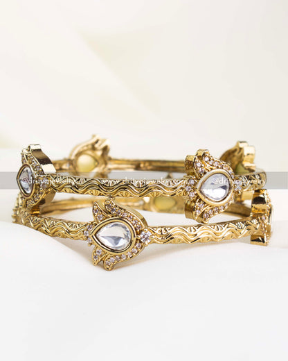 Antique gold kada set with polki-style white stones and filigree-carved edges.