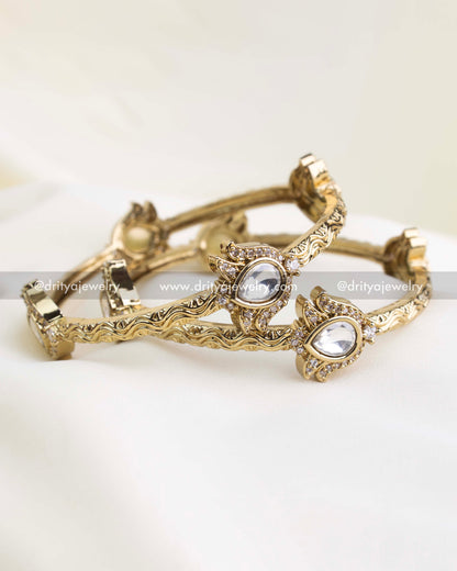 Antique gold kada set with polki-style white stones and filigree-carved edges.