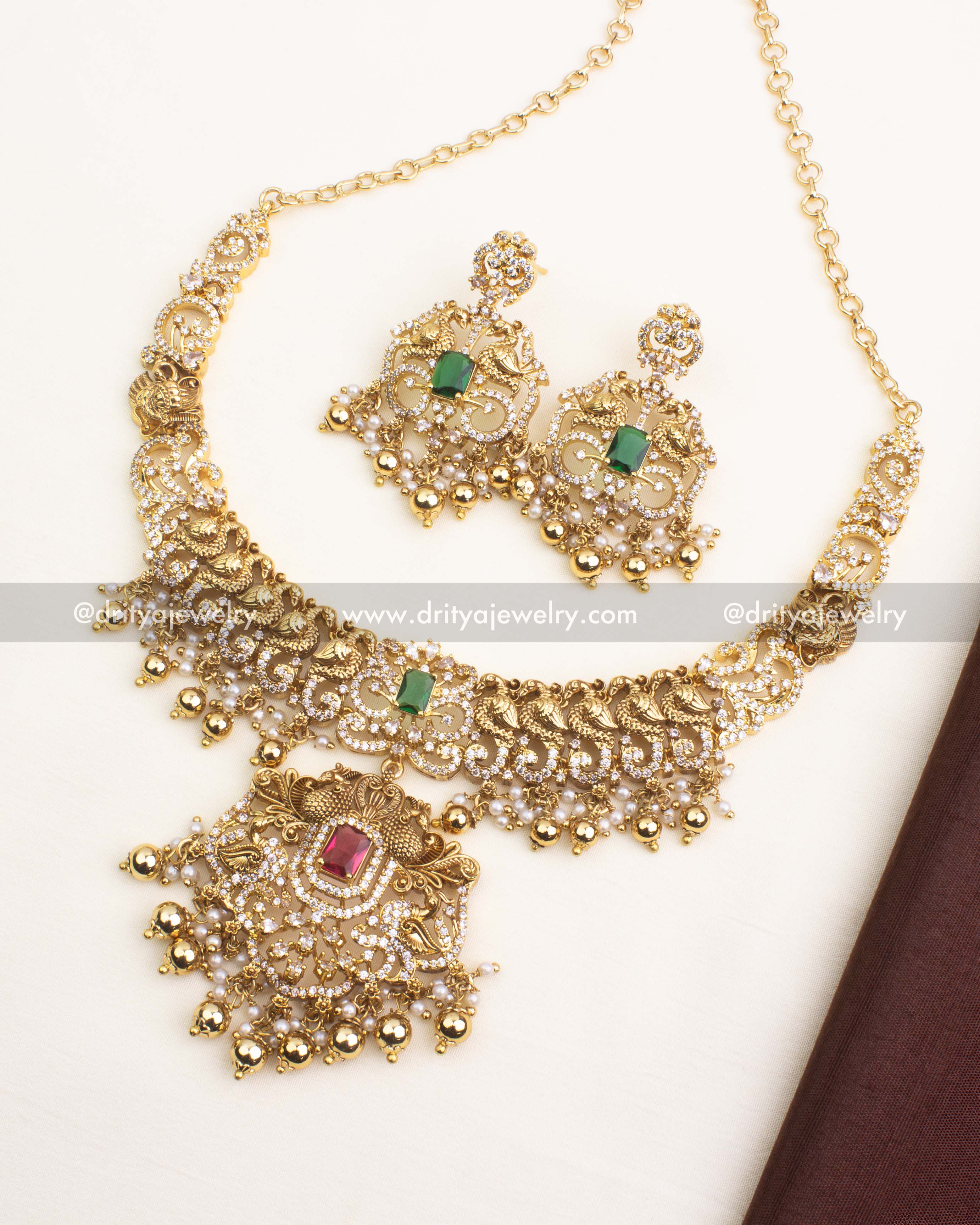 Premium antique short necklace set featuring peacock motifs, red and green CZ stones, and pearl-gold ball hangings.