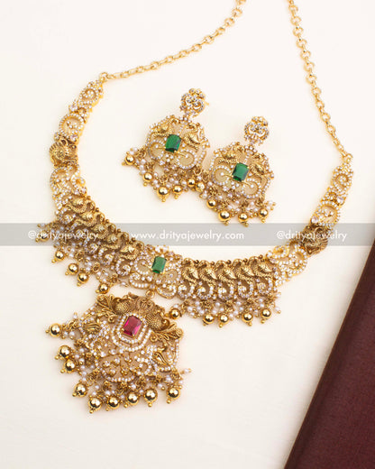 Premium antique short necklace set featuring peacock motifs, red and green CZ stones, and pearl-gold ball hangings.