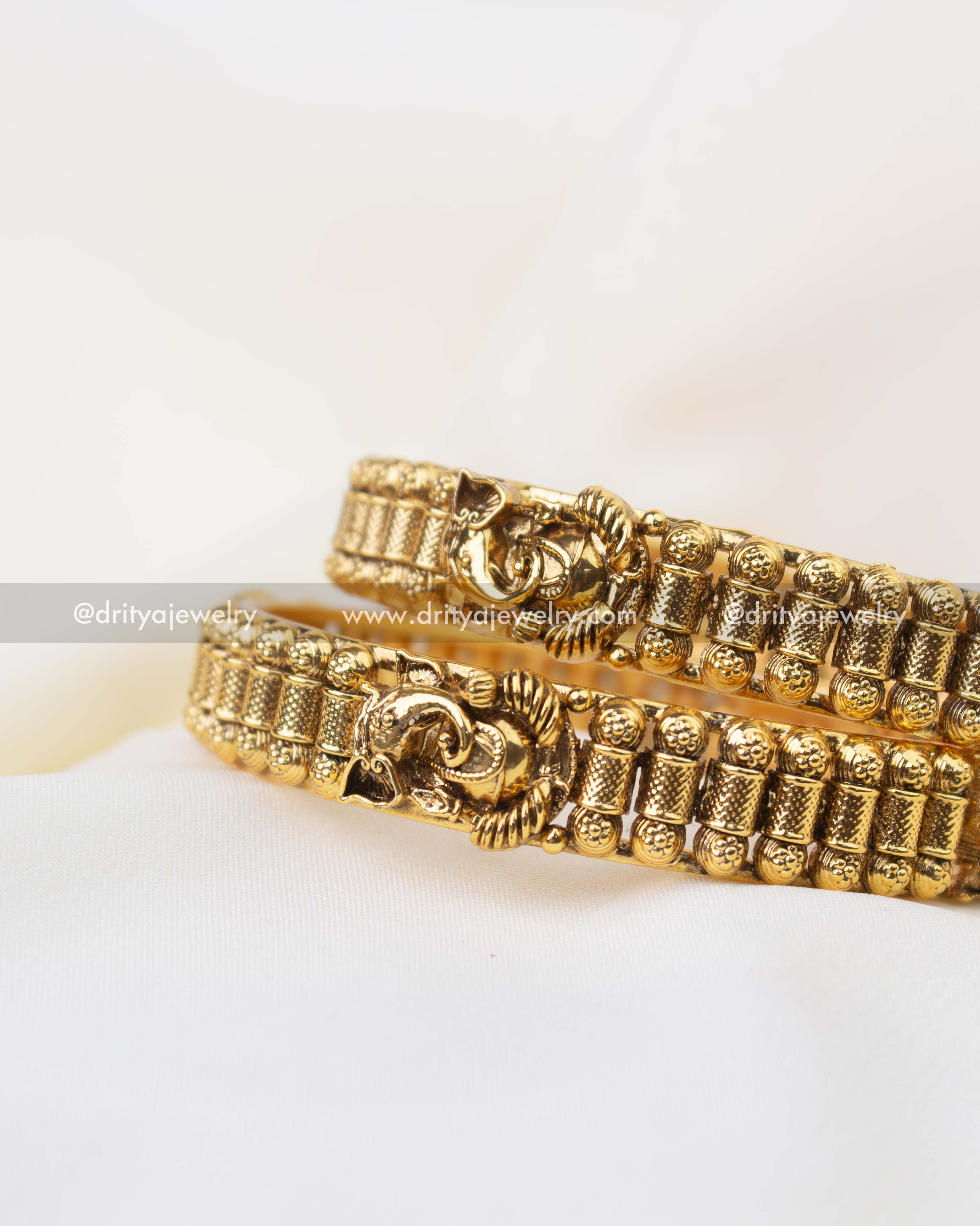 South Indian style antique gold bangles with textured cylindrical patterns and Ganesha motif