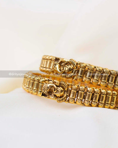 South Indian style antique gold bangles with textured cylindrical patterns and Ganesha motif