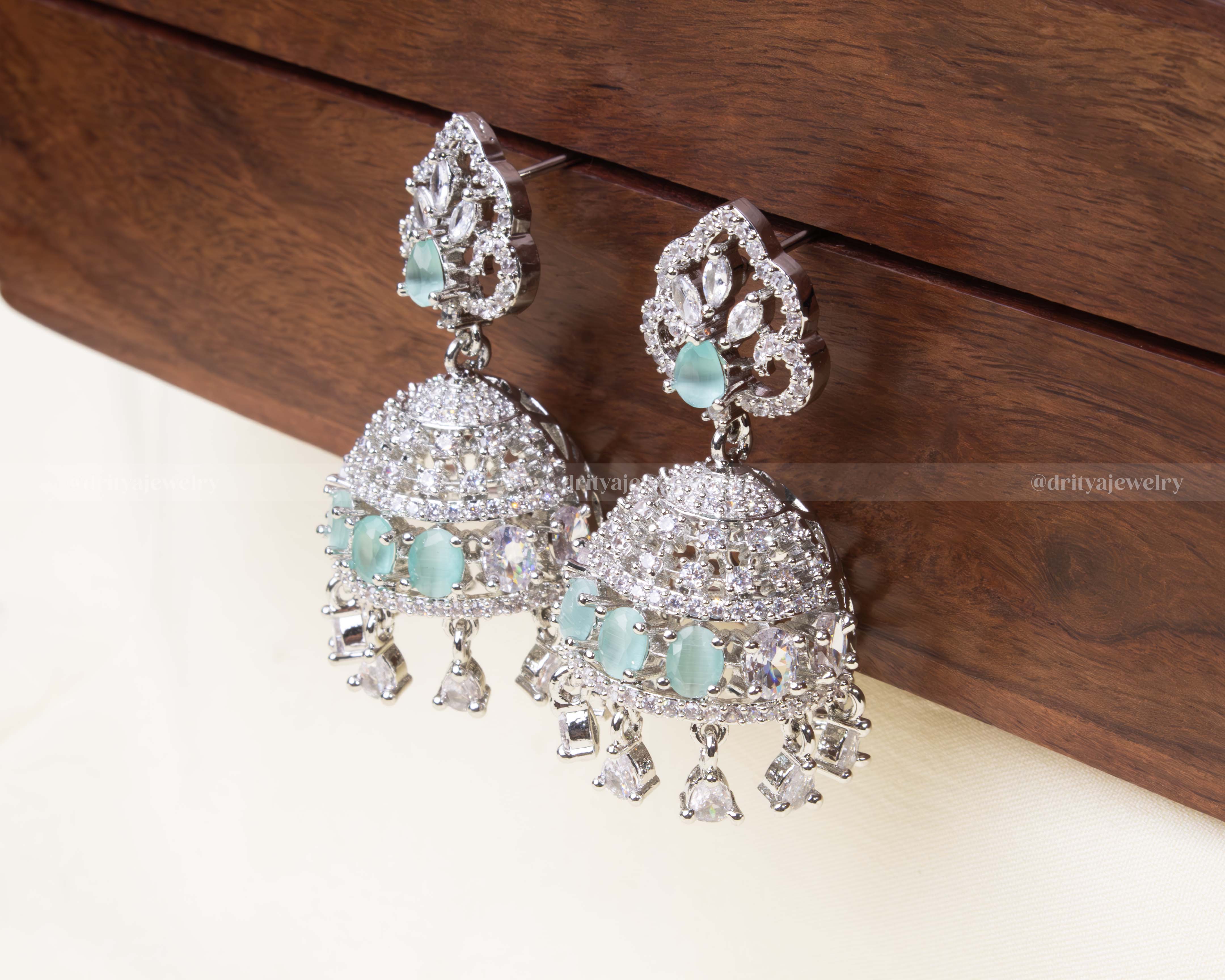 Aqua blue zircon Jhumka set with shimmering AD stones and delicate danglers.