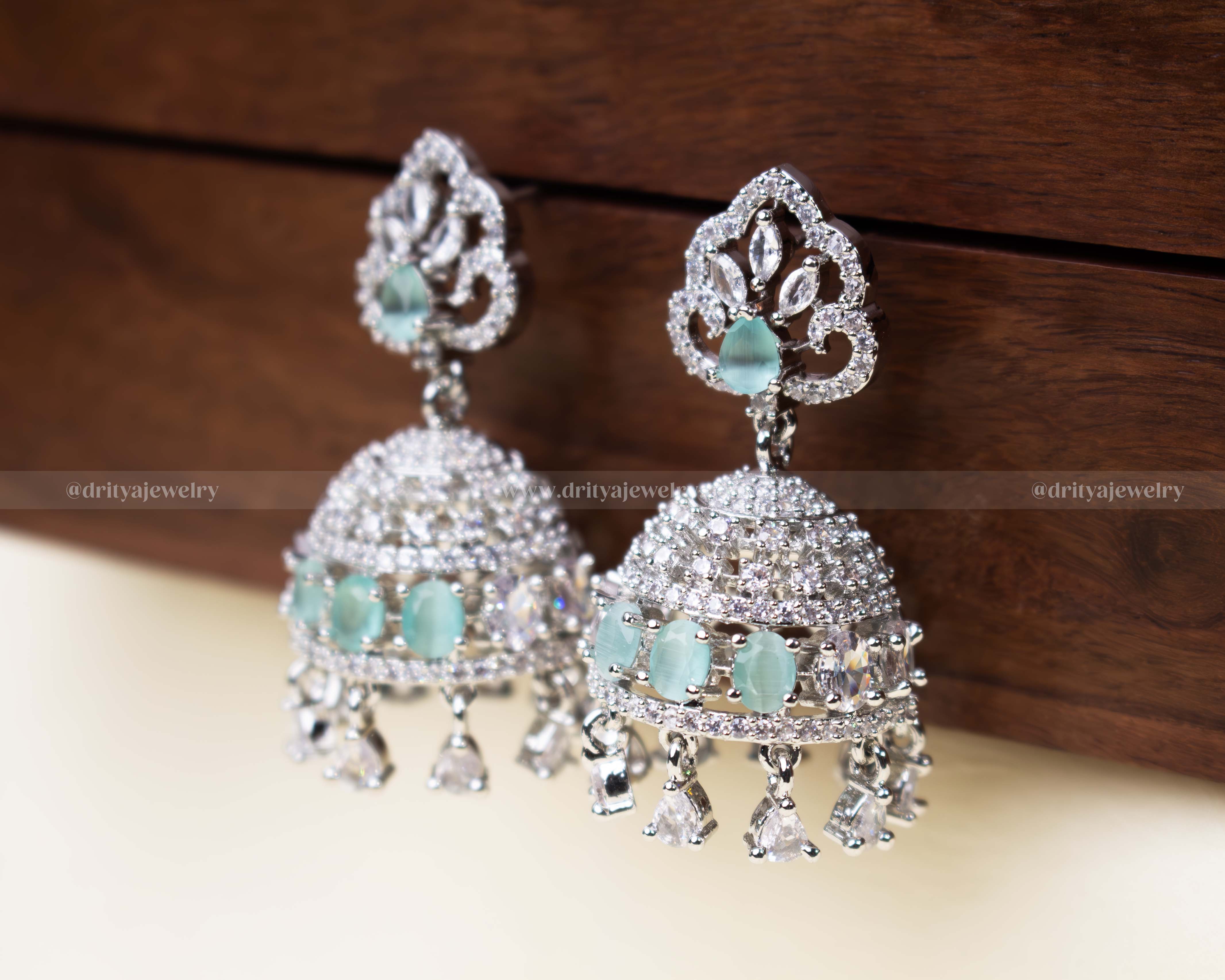 Aqua blue zircon Jhumka set with shimmering AD stones and delicate danglers.