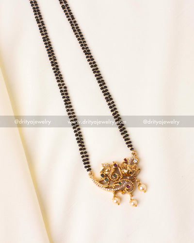 Detailed close-up of the gold-plated peacock pendant with sparkling stones and pearl embellishments on a black beads mangalsutra.